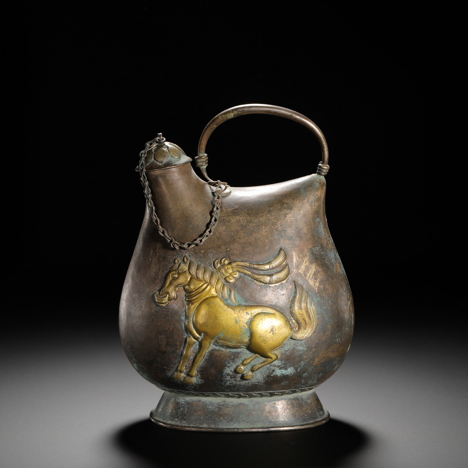 TANG DYNASTY SILVER-GILT LEATHER BAG: HEIGHT:18CM (7.09IN) WIDTH:13.5CM (5.31IN) WEIGHT:420G (0.93LB) SILVER LEATHER-SKIN SHAPED FLASK WITH GILDED DANCING HORSE RELIEF, TANG DYNASTY. EQUIPPED WITH A HANDLE AND CHAIN LID, MODELED AFTER NOM