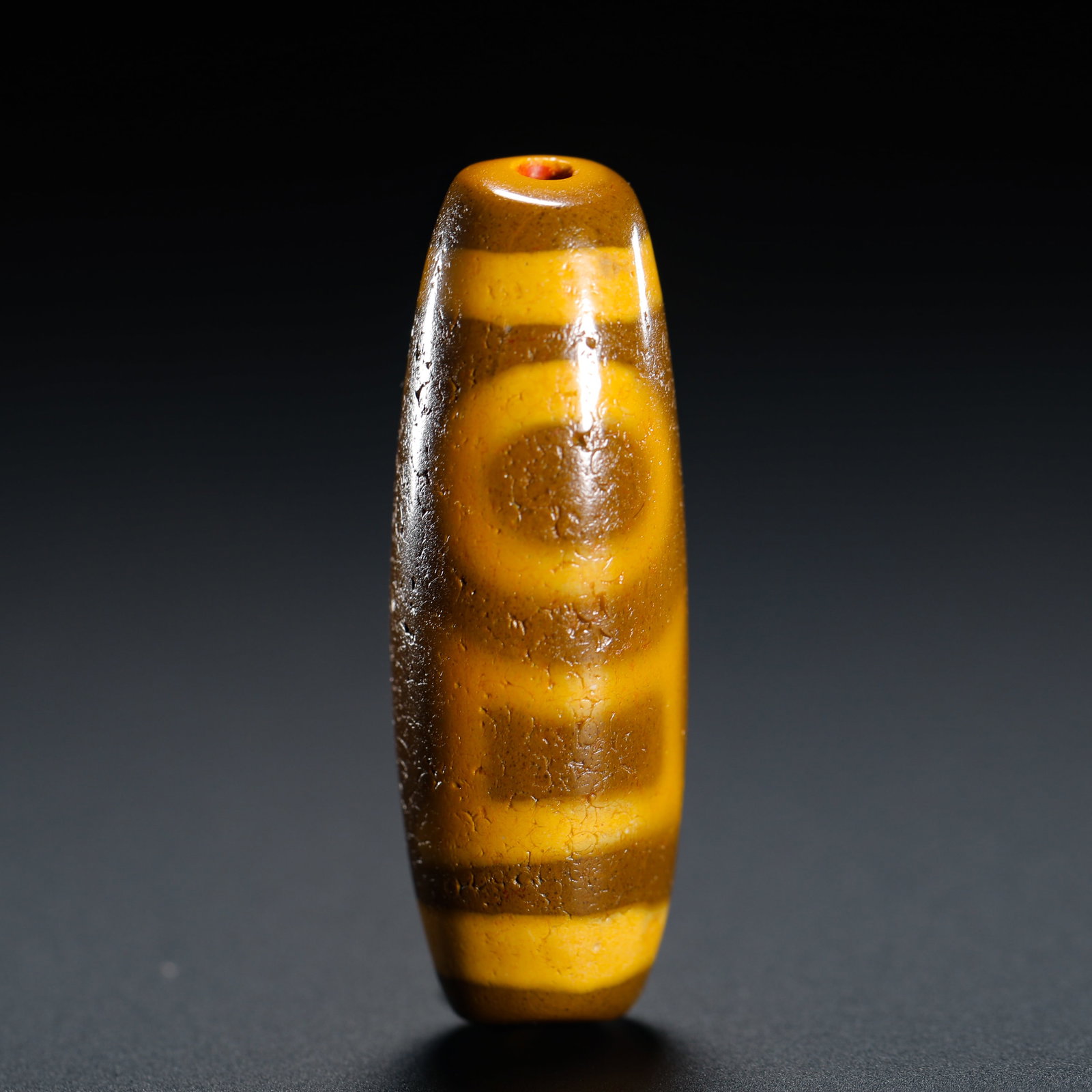 TANG DYNASTY HEAVEN AND EARTH TWO EYES HEAVEN PEARL SINGLE BEAD: HEIGHT:3.5CM (1.38IN) DIAMETER:1.2CM (0.47IN) WEIGHT:10G (0.02LB) ANTIQUE HEAVEN-EARTH TWO-EYE DZI BEAD, BARREL-SHAPED. DARK BROWN BASE WITH BRIGHT YELLOW ETCHED TOTEMS: ONE UPPER EYE, ONE SQUARE LOWE