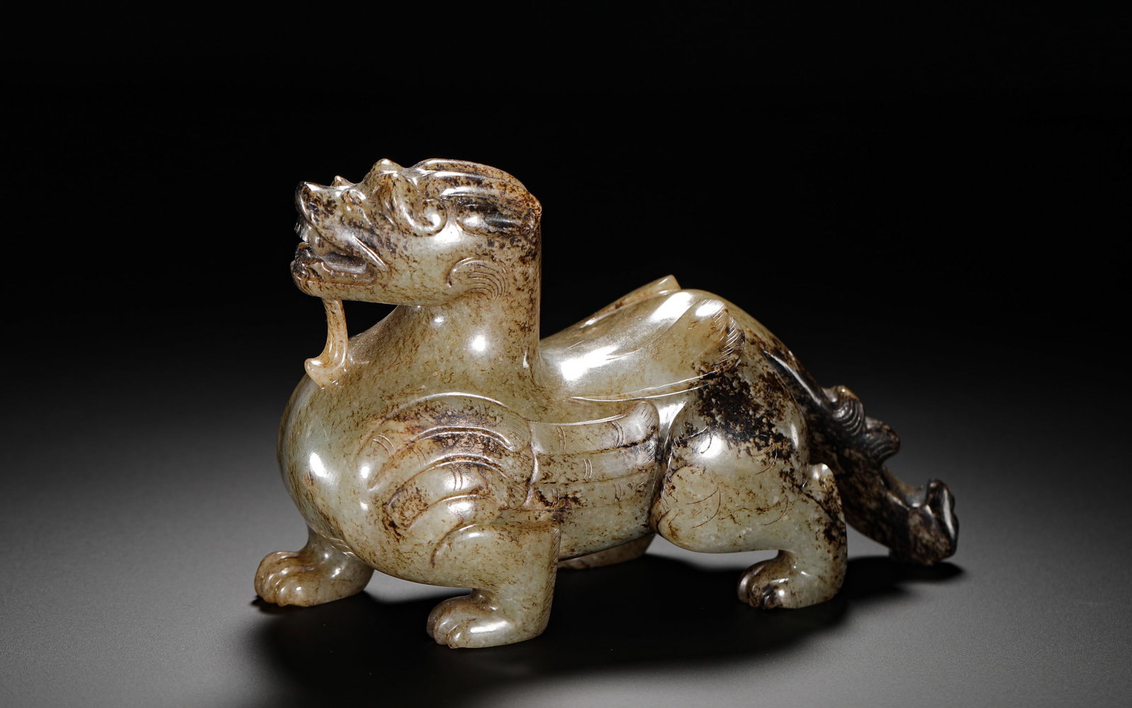 HAN DYNASTY HETIAN JADE BLACK IMPREGNATED TIANLU WARD OFF EVIL DOUBLE-WINGED AUSPICIOUS BEAST: HEIGHT:10CM (3.94IN) WIDTH:16CM (6.30IN) WEIGHT:790G (1.74LB) ARCHAIC HETIAN JADE WINGED TIANLU MYTHICAL BEAST ORNAMENT WITH NATURAL DARK RUSSET INCLUSIONS.INTEGRALLY CARVED FROM A SINGLE JADE BLOCK, 