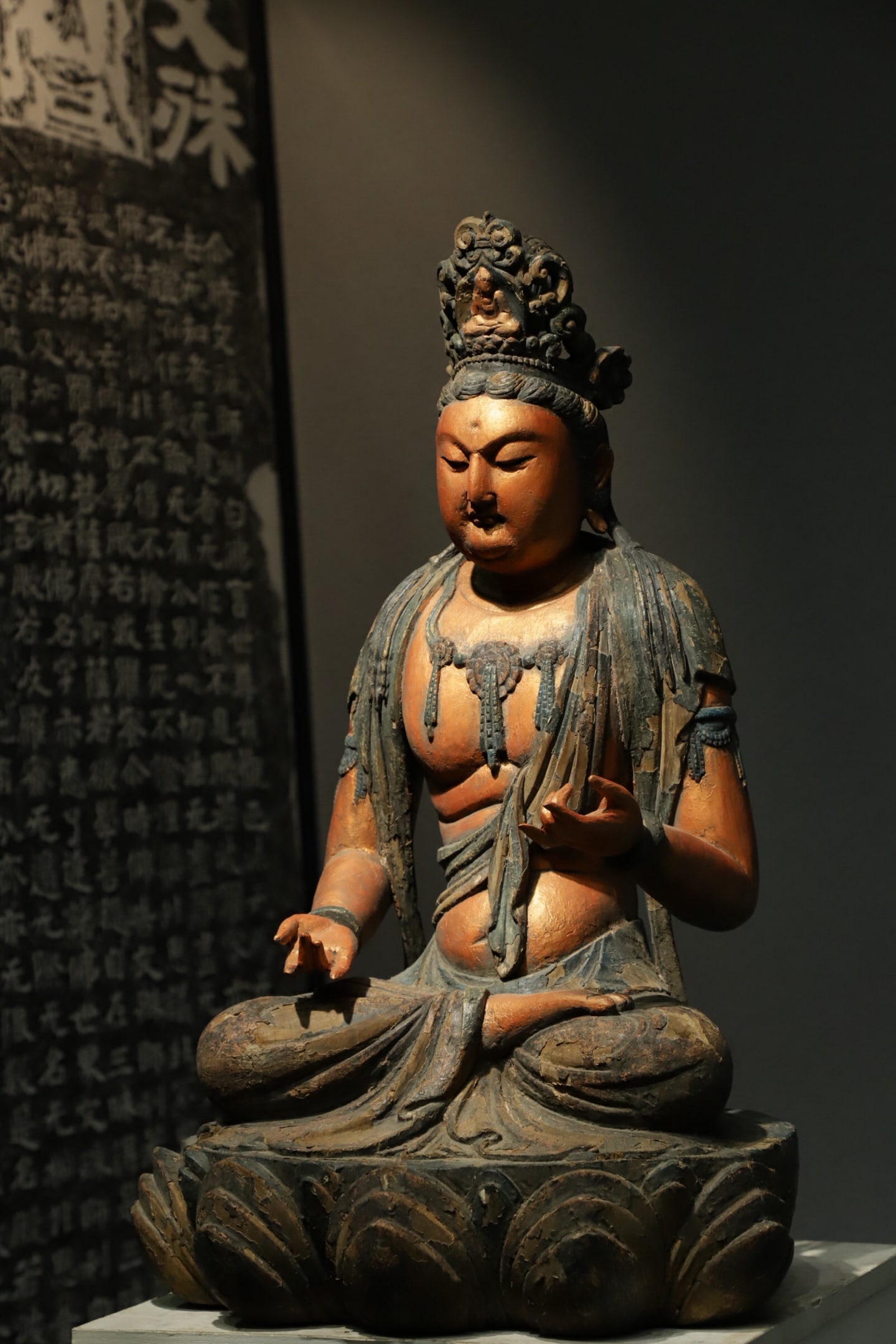 A TANG DYNASTY WOODCARVING OF A BODHISATTVA SITTING ON A LOTUS: H:68L:42CMW:33CM THE GUANYIN STATUES OF THIS PERIOD NOT ONLY RETAINED THE RITUAL FEATURES OF INDIAN BUDDHIST STATUES BUT ALSO DEEPLY INTEGRATED THE AESTHETIC INTERESTS OF THE CENTRAL PLAINS HAN REGION