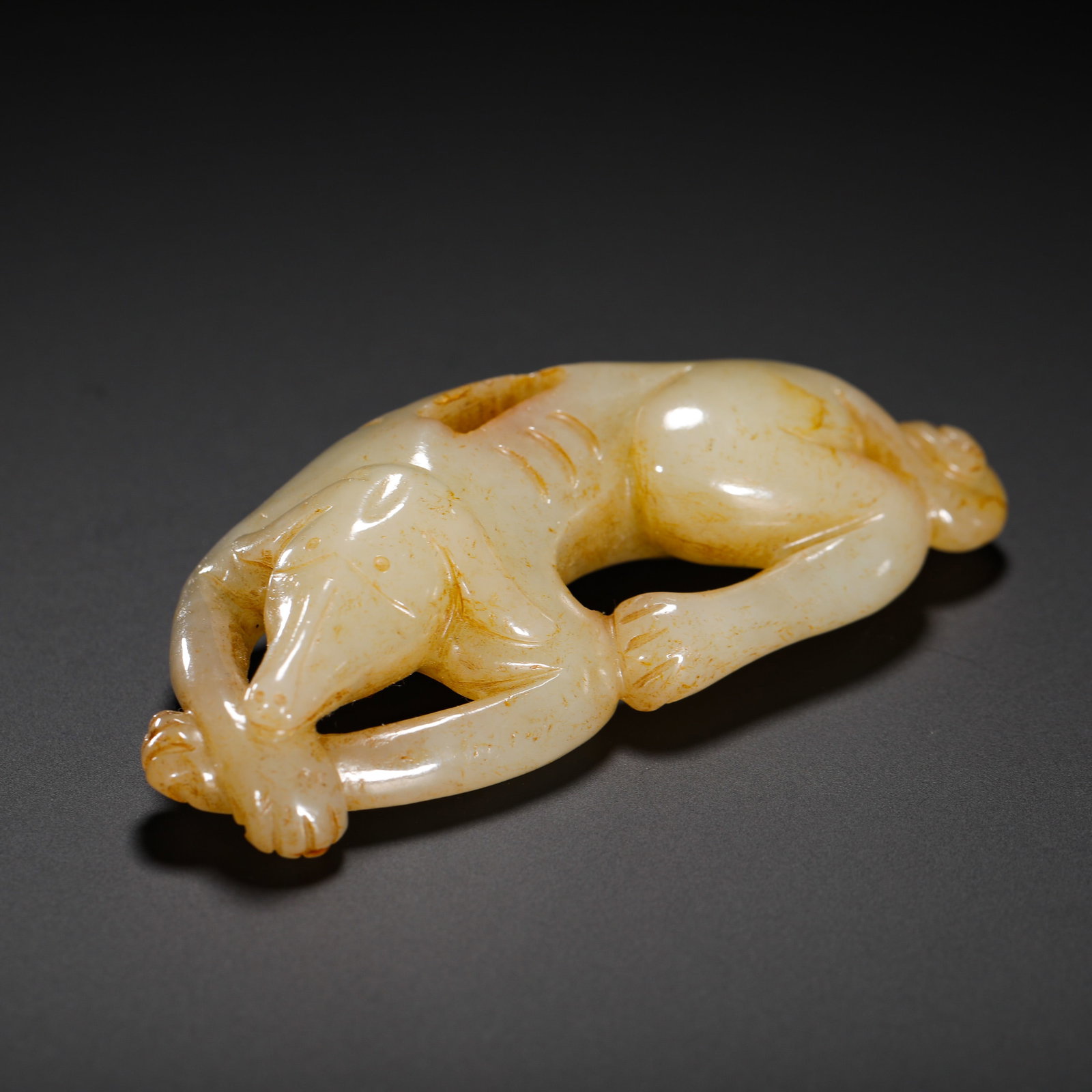 TANG DYNASTY HETIAN JADE RED JADE DOG: HEIGHT:4CM (1.57IN) WIDTH:8.5CM (3.35IN) WEIGHT:70G (0.15LB) ARCHAIC HETIAN WHITE JADE RECUMBENT DOG PENDANT WITH NATURAL RUSSET STAINS.CARVED FROM TRANSLUCENT MILD JADE WITH NATURAL YELLOW-BROWN VEIN
