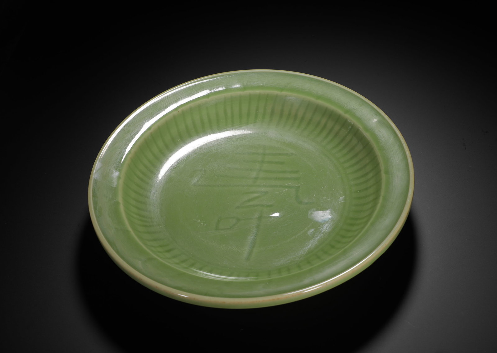 YUAN LONGQUAN KILN CELADON PLATE ENGRAVED WITH THE CHARACTER "LONGEVITY": H:5.5CM (2.17IN) D:27CM (10.63IN) WEIGHT:1310G (2.89LB) THIS IS A YUAN DYNASTY PORCELAIN DISH FROM THE LONGQUAN KILN. IT IS COVERED IN A RICH, JADE-LIKE CELADON GLAZE, WITH A "SHOU" (LONGEVITY) CHARAC