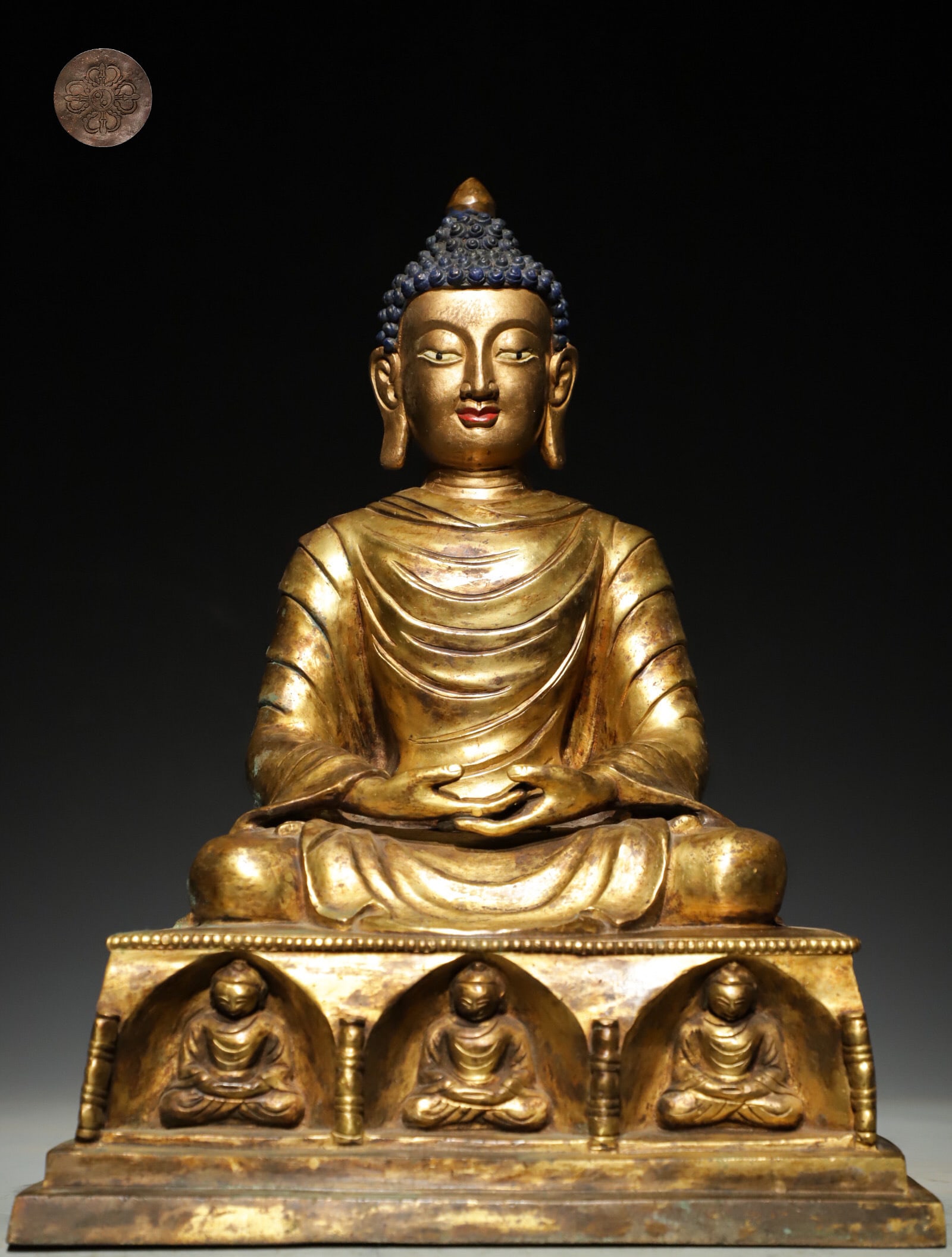 A GILDED BRONZE STATUE OF SAKYAMUNI BUDDHA FROM THE MING DYNASTY: H: 33CM (12.99IN) L: 25CM (9.84IN) W: 19CM (7.48IN) WEIGHT: 7350G (16.20LB) FULLY GILDED BRONZE FIGURE. THE BUDDHA??S SPIRAL HAIR IS PAINTED BLUE, WITH A MILD AND MERCIFUL FACIAL EXPRESSION. DRAPED IN