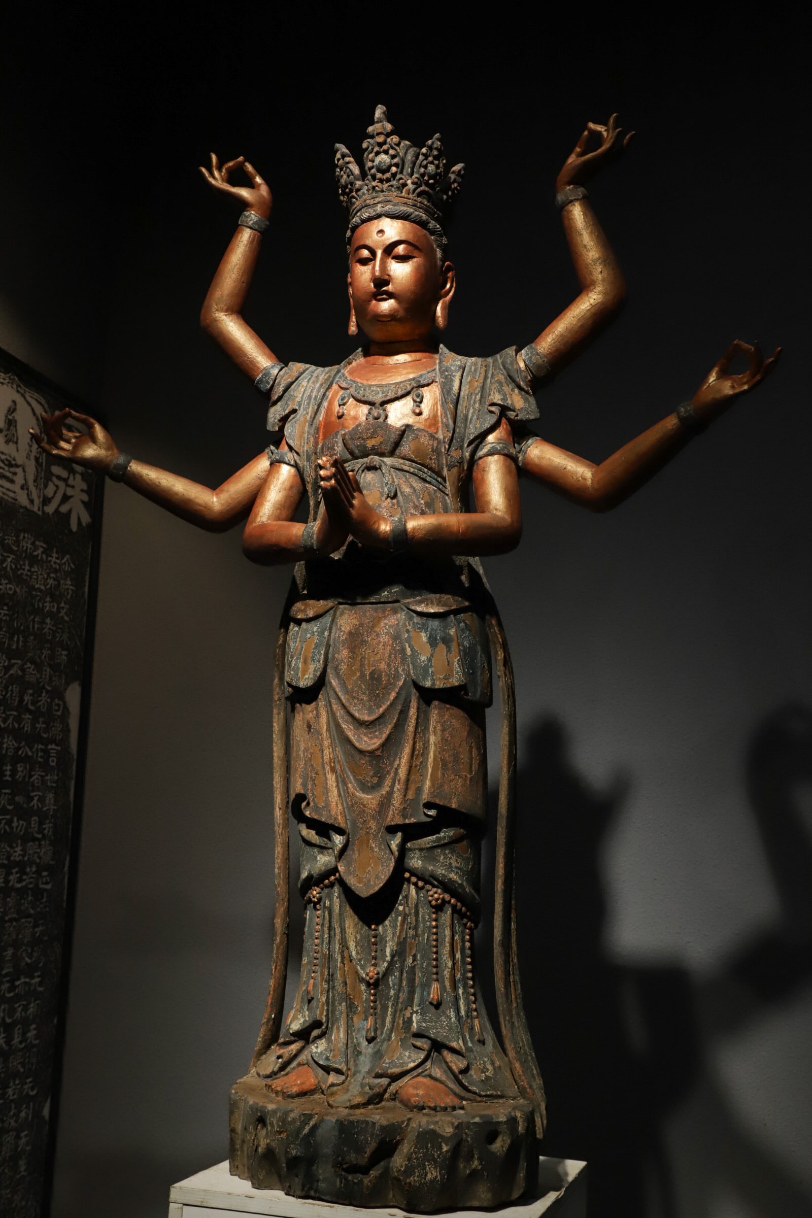 A WOODCARVING OF THE MING DYNASTY, AN EIGHT-ARMED GUANYIN STANDING FIGURE: H:130CM (51.18IN) L:100CM (39.37IN) W:40CM (15.75IN) THE SOLID HEAVY WOOD BEARS DEEP MILD ANCIENT PATINA AFTER CENTURIES OF EROSION WITH NATURALLY FADED ORIGINAL GILDING AND MINERAL PIGMENT RELICS, PR