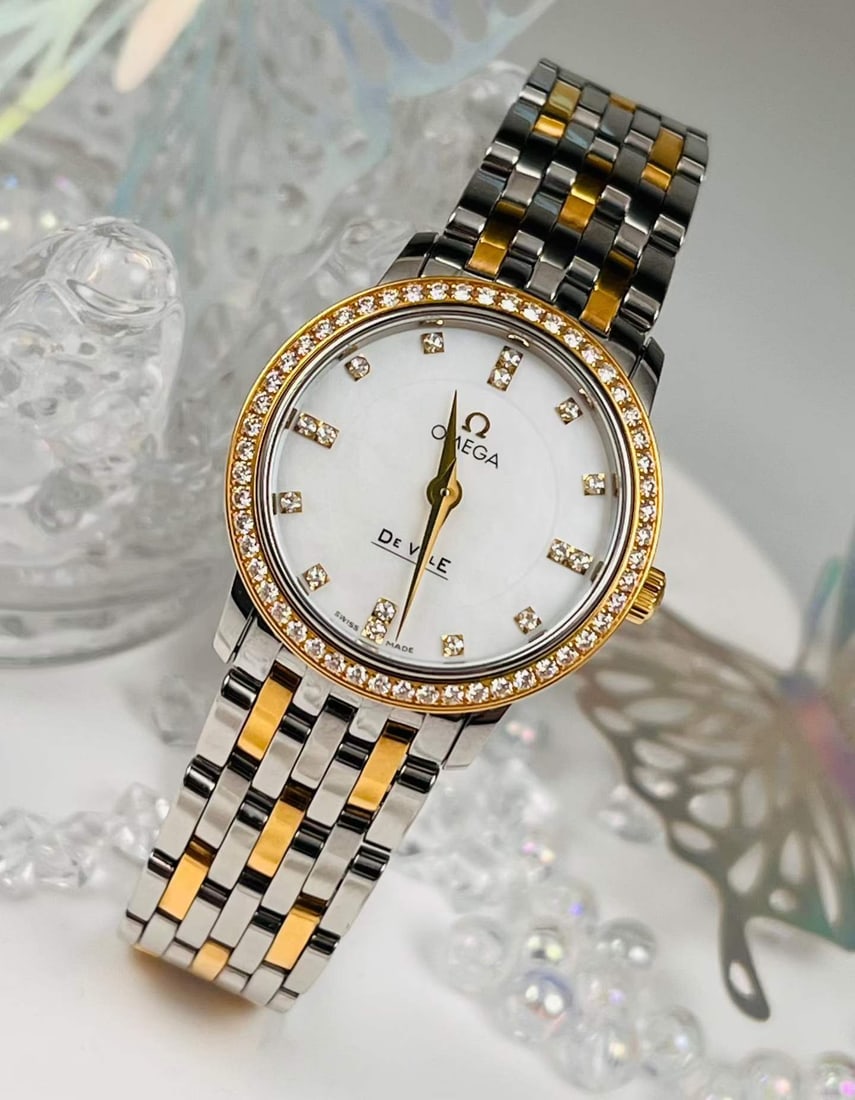 OMEGA DE VILLE COLLECTION LADIES' WATCH: Name Omega De Ville Collection Ladies' Watch Dimensions 18K Yellow Gold Diamond-Set Bezel, Mother-of-Pearl Dial with Diamond Hour Markers D:27mm