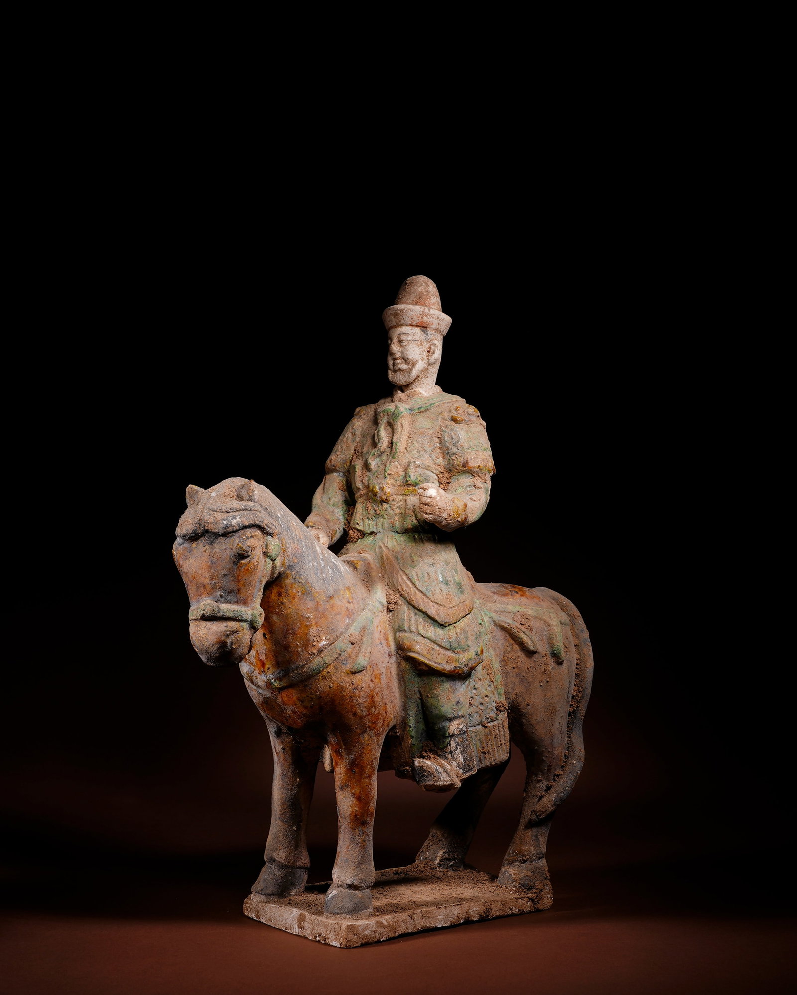 MING TRI-COLOR TERRACOTTA WARRIORS ON HORSEBACK: L:24.5cm H:34.5cm This is a low-temperature lead-glazed tri-color burial figurine of a Western Hu foreigner riding horse, made of white pottery clay and integrally fired with rectangular base, coated 