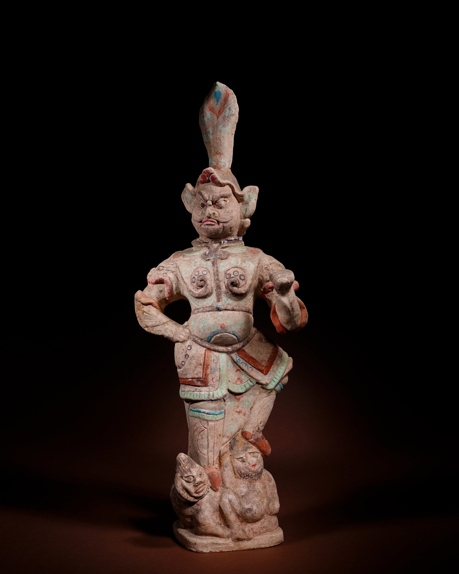 TANG DYNASTY PAINTED FIGURES OF THE HEAVENLY KING AND HIS GUARDIAN: L:18cm H:50cm This painted pottery heavenly king figurine of Tang Dynasty is molded in separate clay pieces and assembled on an integrated base, decorated with mineral pigments of red, green, blue and