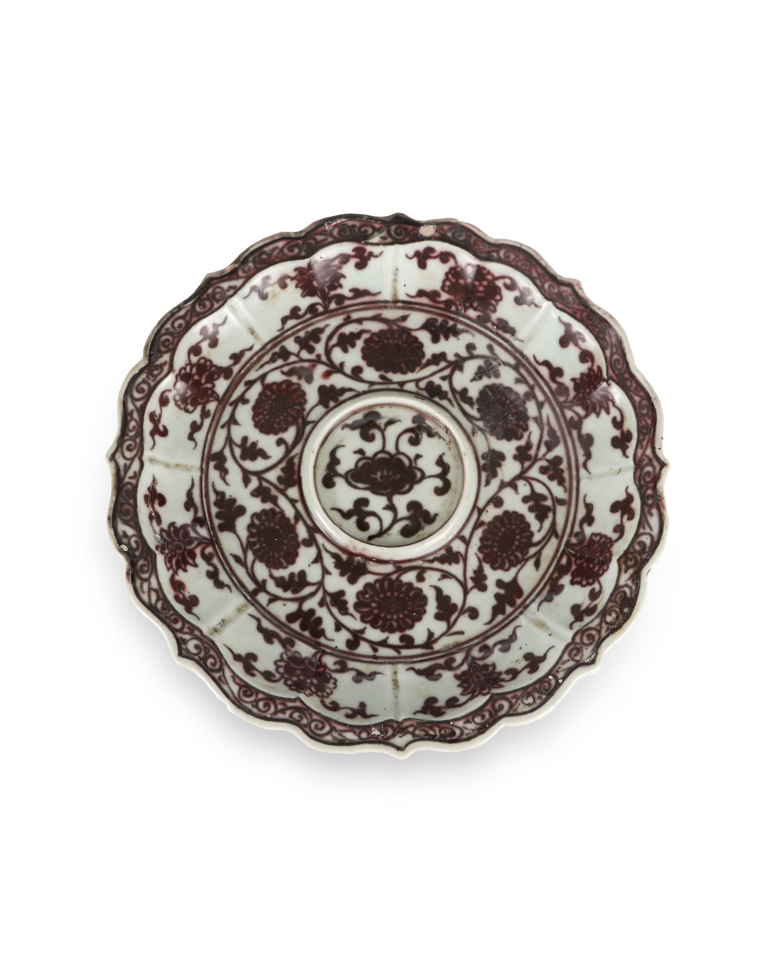 YUAN DYNASTY UNDERGLAZE RED ENTWINED CHRYSANTHEMUM-PATTERNED RHOMBUS-SHAPED SAUCER: H:3cm W:20.3cm A Yuan-dynasty rhombus flower-shaped cup stand for tea set. It has lobed flared rim, white glaze base fully decorated with multi-layer underglaze red patterns. The central lotus platfor
