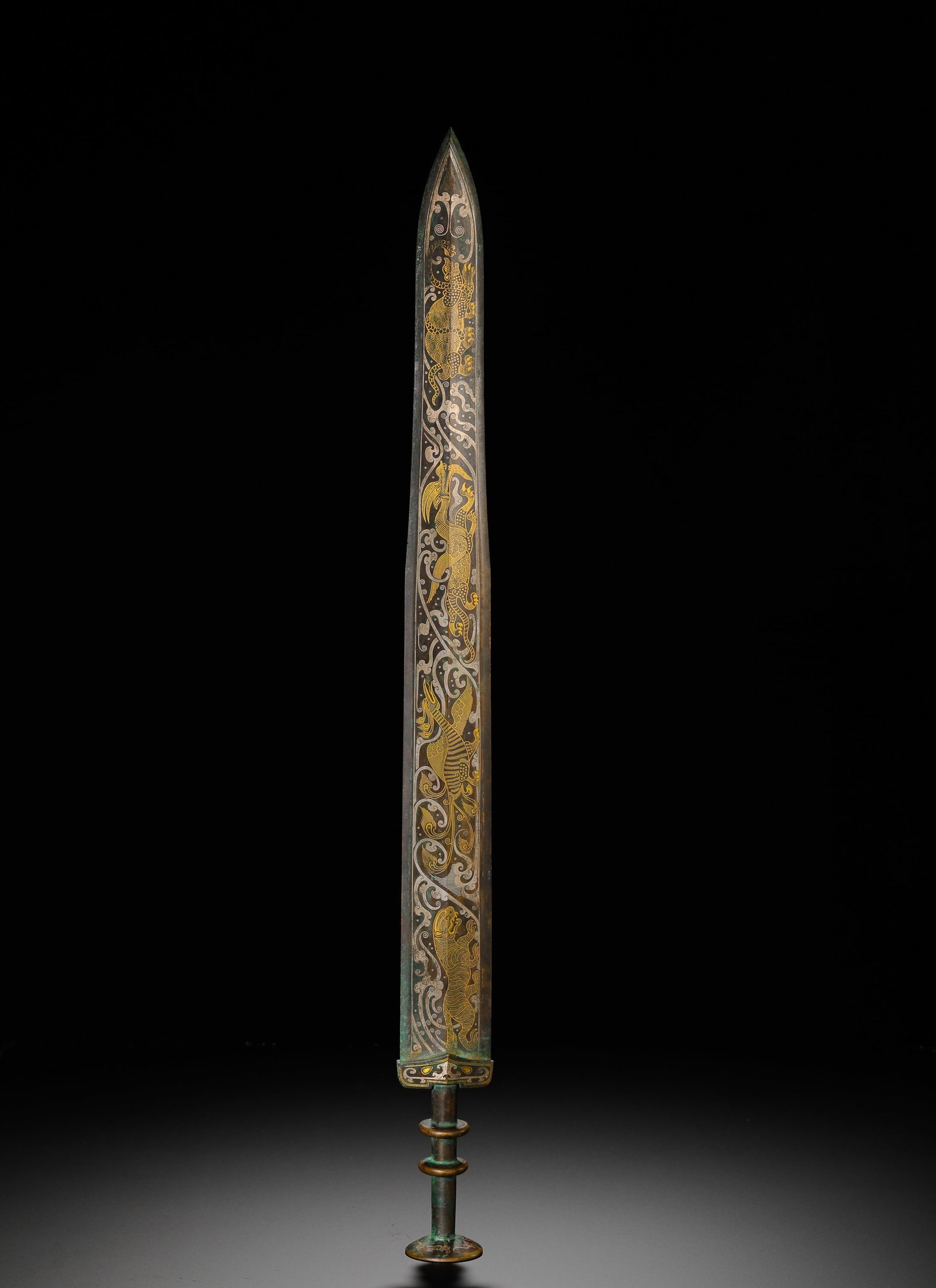 BRONZE SWORD WITH INSCRIPTIONS OF GOLD AND SILVER FROM THE WARRING STATES PERIOD: Long:60cm (23.62in) Weight:1010g(2.23lb)Warring States bronze long sword inlaid with gold and silver dragon, phoenix and auspicious beast patterns. The blade features gold-inlaid dragons, phoenixes an
