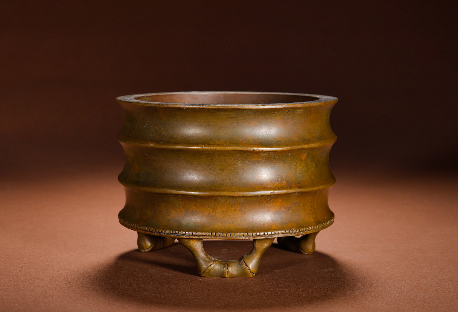 BRONZE BAMBOO JOINT THREE-LEGGED TUBE FURNACE OF THE QING DYNASTY: Height:9.5cm Width:12.5cm Weight:1360gBronze Cylindrical Censer with Three Bamboo-joint Feet, a classic imitative Xuande censer. Integrally cast from refined copper, its body is molded in segmented ba