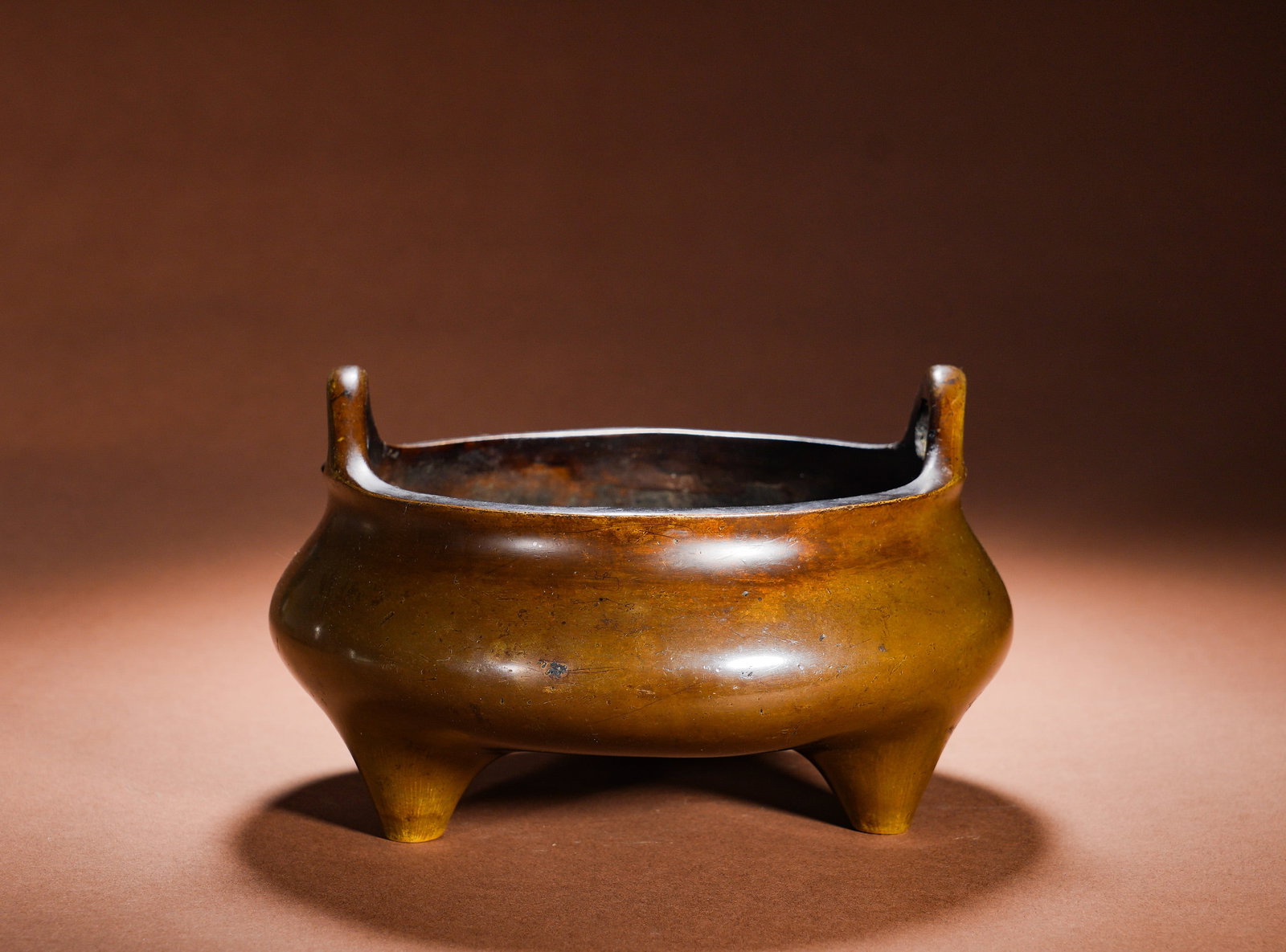BRONZE THREE-LEGGED FURNACE WITH SKY-PIERCING EARS IN THE QING DYNASTY: Height:11.5cm Width:20cm Weight:2490gBronze Tripod Censer with Upright Loop Handles, a classic Xuande censer form. Cast integrally from refined copper, it features a pair of symmetrical upright loop h