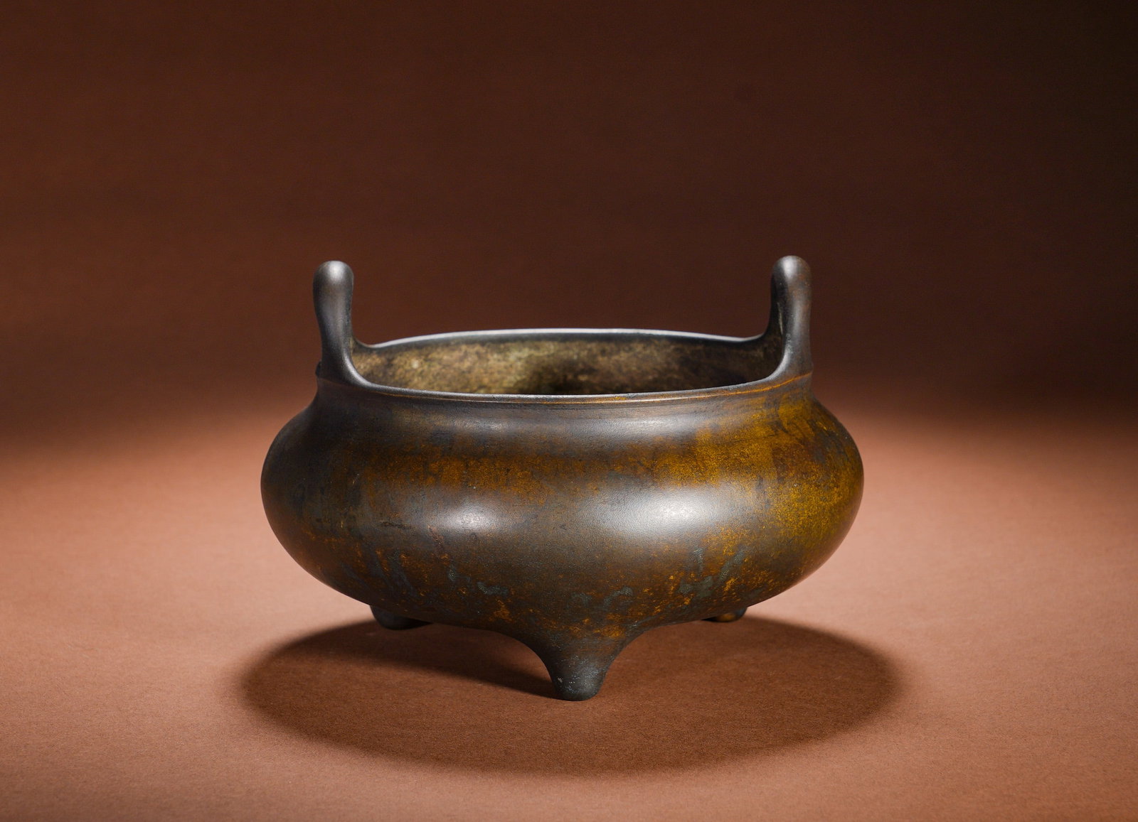 A COPPER THREE-LEGGED FURNACE WITH A HIGH EAR IN THE MING DYNASTY: Height:11.5cm Width:18cm Weight:1330gBronze Tripod Censer with Upright Loop Handles, a standard classic Xuande censer form. The whole vessel is integrally cast from refined copper, fitted with a pair 