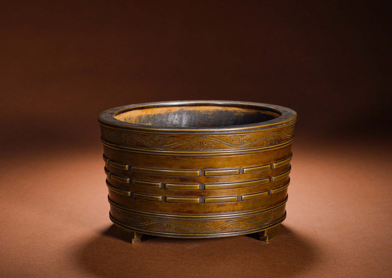 BRONZE EIGHT-TRIGRAM PATTERNED TUBE THREE-LEGGED FURNACE OF THE MING DYNASTY: Height:11cm Width:17.8cm Weight:2930gCast from refined copper, it adopts a straight cylindrical shape with wide flat folded rim, supported by three short square feet at the bottom for stable placement
