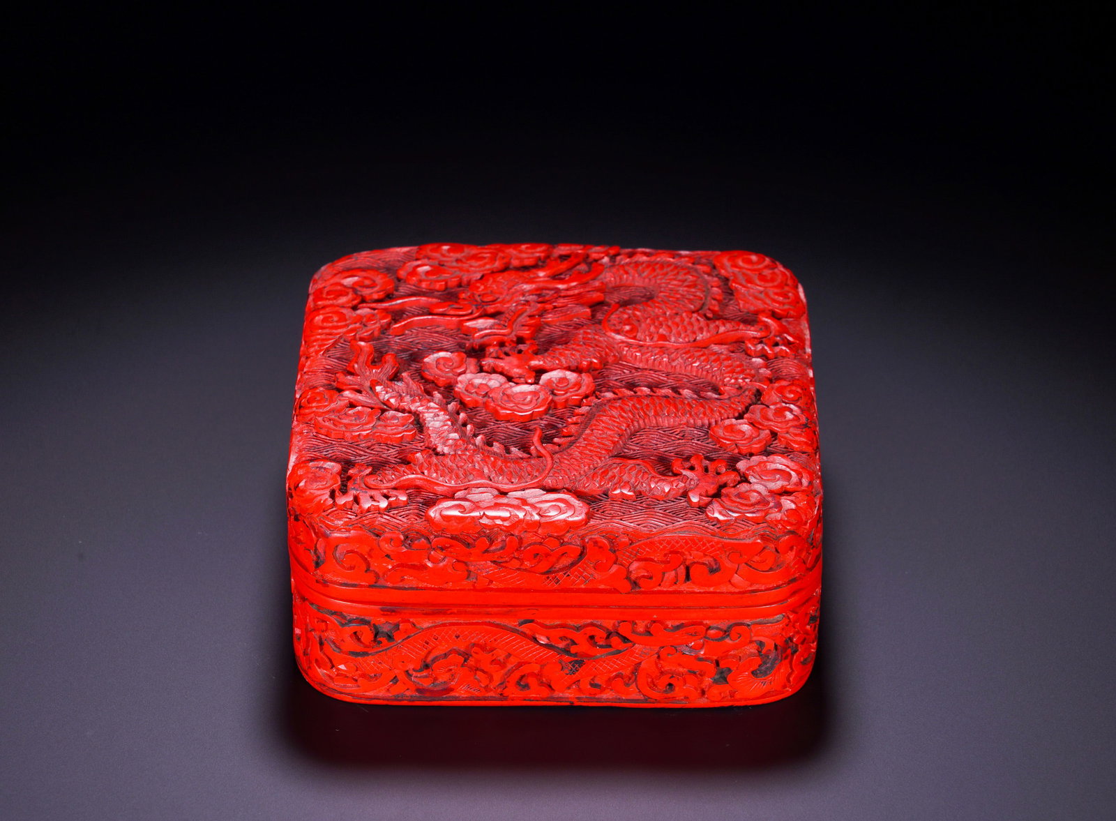 QING DYNASTY RED AND CLOUD-DRAGON PATTERN SQUARE LID BOX: Height:5.5cm (2.17in)Width:13.45cm (5.30in)Weight:370g(0.82lb)Qing Dynasty carved red lacquer square box with dragon and cloud patterns.The rounded-square lidded box features tight-fitting cover. The 