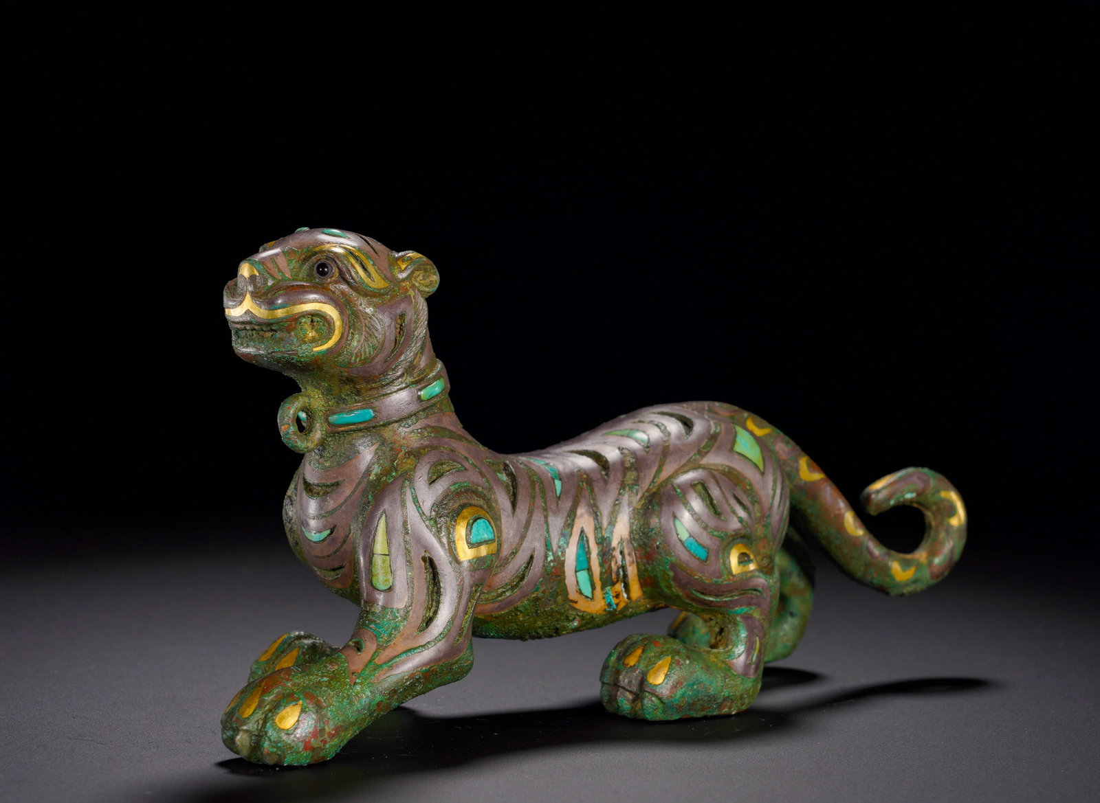 HAN DYNASTY BRONZE INLAID WITH GOLD AND SILVER INLAID WITH TURQUOISE RUNNING TIGER: Height:8.5cm (3.35in)Width:17cm (6.69in)Weight:1090g(2.40lb)The striding tiger turns its head backward with imposing bearing, fitted with ring collar. Gold and silver lines depict stripes, inlaid with