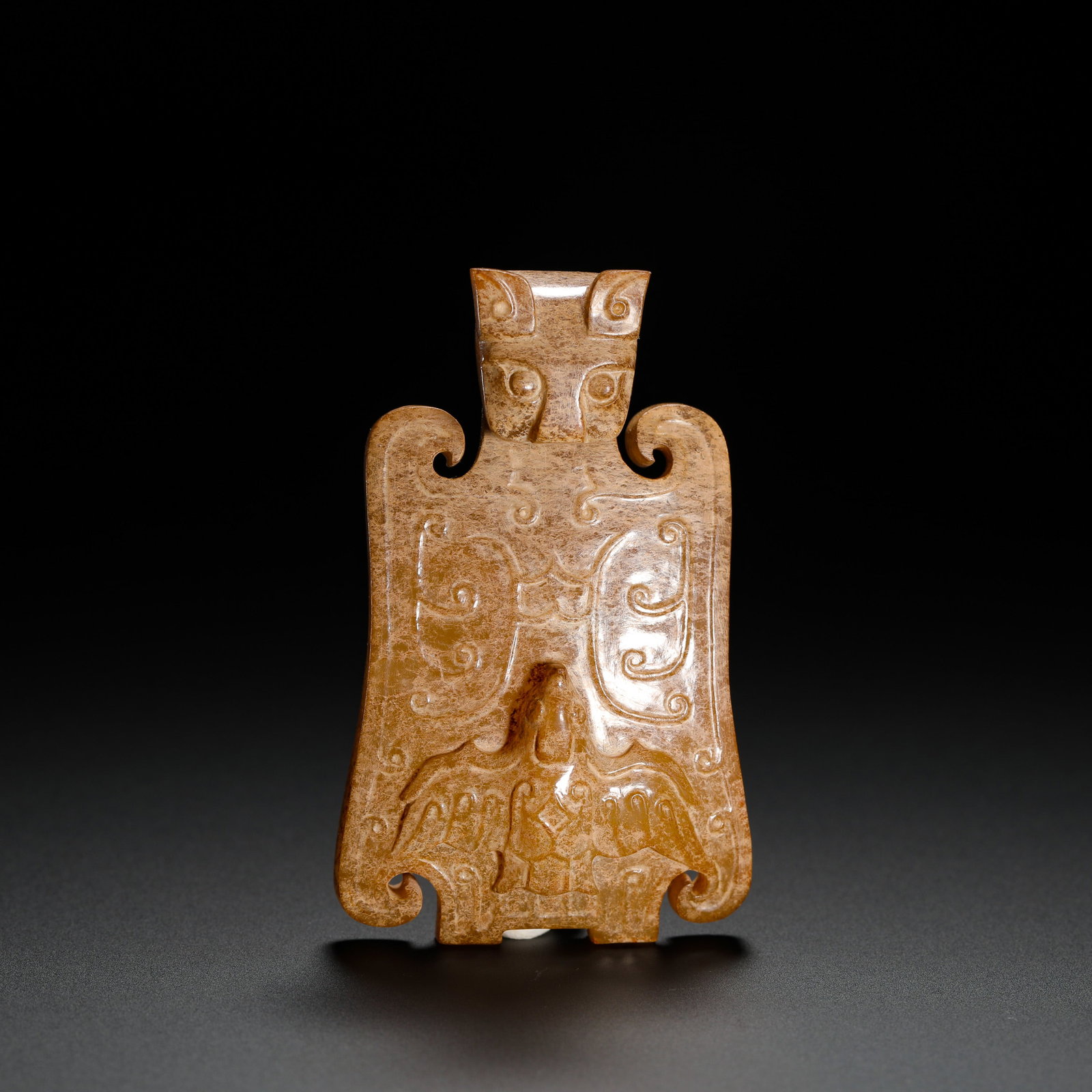 SHANG AND ZHOU JADE-FACED DIVINE BIRD COMPOSITE PENDANT: Height:6.5cm (2.56in) Width:4cm (1.57in) Weight:46g(0.10lb)Shang-Zhou jade ritual pendant carved with beast mask and sacred bird. Flat single-piece jade, three-dimensional beast mask crown, twin drago