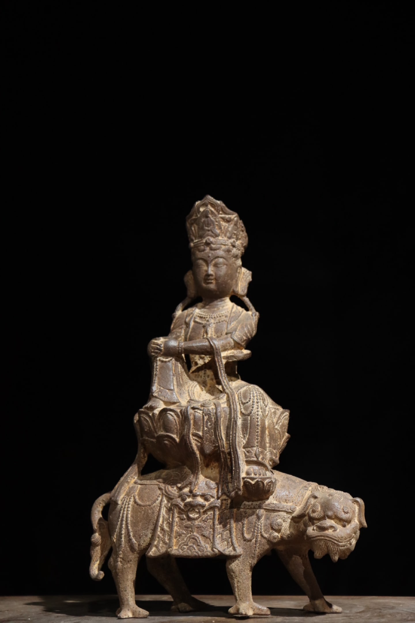 CAST IRON MANJUSRI BODHISATTVA RIDING A LION FROM THE MING DYNASTY: H:34cm (13.39in)Cast integrally from pig iron via mould casting; Manjushri sits atop lotus flower mounted on lion??s back, covered with aged natural rust, a devotional statue for folk shrine worship i
