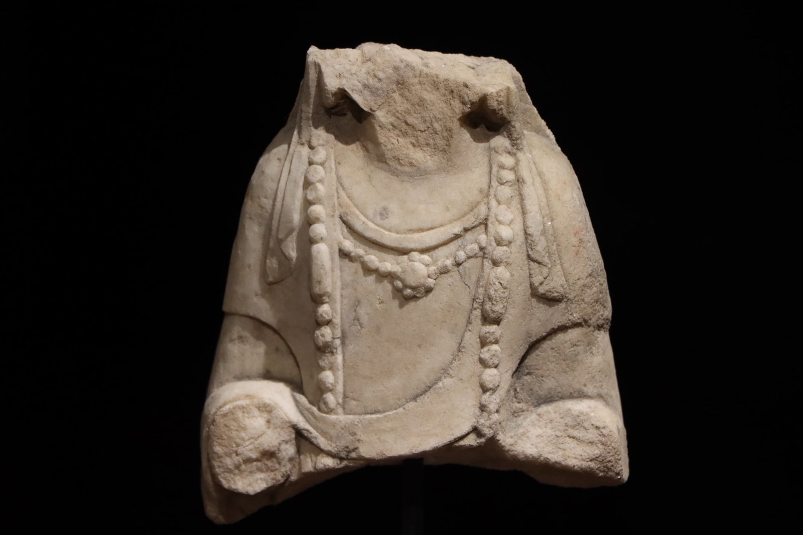 A WHITE MARBLE STATUE OF A BODHISATTVA FROM THE NORTHERN QI DYNASTY WITH A BROKEN UPPER BODY: H:30cm (11.81in) H:17cm (6.69in) W:15cm (5.91in) Carved from a single block of white marble; only torso and partial arms remain, adorned with two layers of finely incised beaded necklaces, a surviving