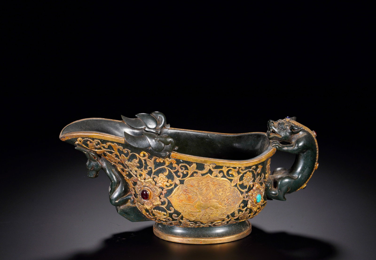 HAN DYNASTY JADE INLAID WITH GOLD CHILONG BEAST HEAD : Height:12cm (4.72in) Width:26cm (10.24in) Weight:1170g(2.58lb)Modeled after ancient bronze gong wine vessel. Dark jade body decorated with openwork gilt floral scrolls inlaid with agate and turquoise.