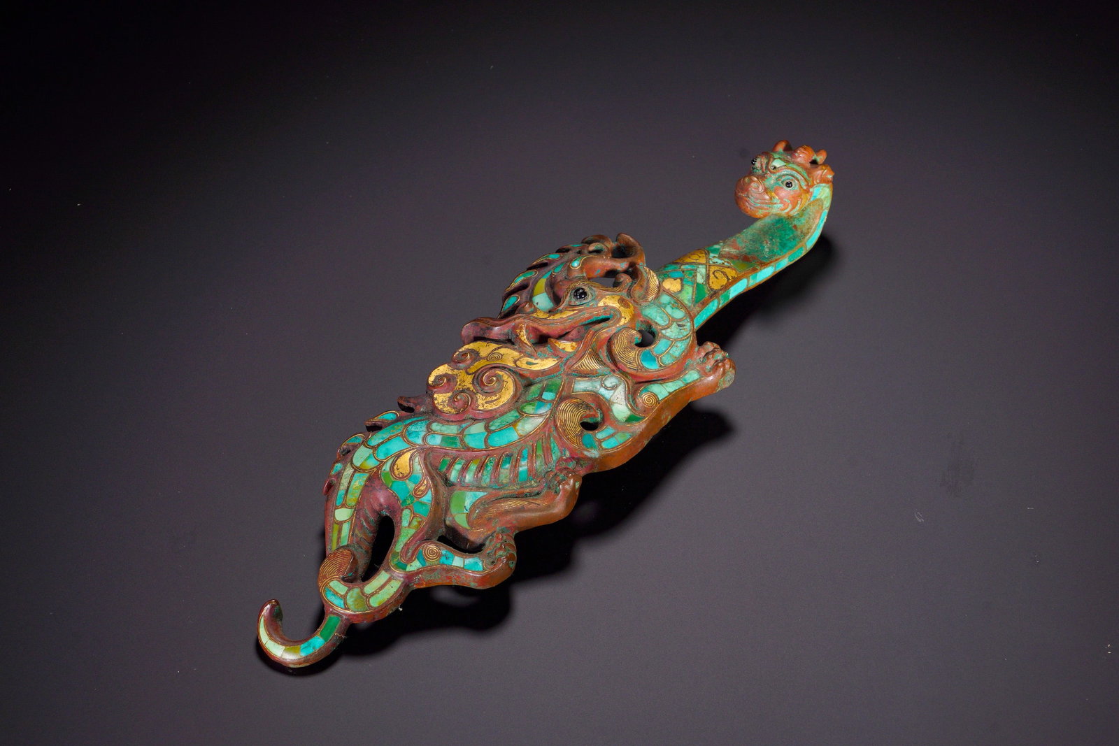 BRONZE OF THE HAN DYNASTY WITH GOLD INLAID WITH TURQUOISE HOOKS: Height:7.5cm (2.95in)Width:23cm (9.06in)Weight:440g(0.97lb)The openwork belt hook features intertwined dragon and mythical beast, beast forming the hook head. Gold lines delineate scroll and fur patte