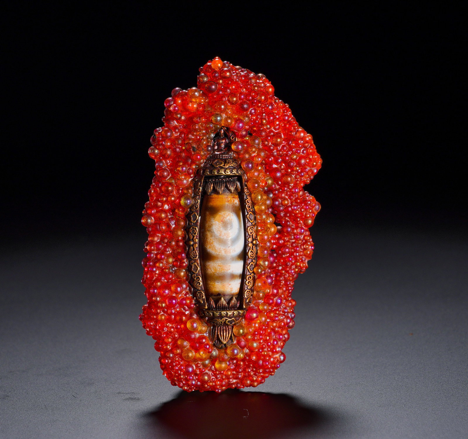 GLAZED MILLET GRAIN INLAID SKY PEARL RELIC PENDANT: Height:8.1cm (3.19in) Width:4.4cm (1.73in) Weight:40g(0.09lb)Formed by dense orange glass beads. A gilt bronze lotus niche holds a sacred dzi bead, crowned with miniature Buddha statue. Glass belongs 