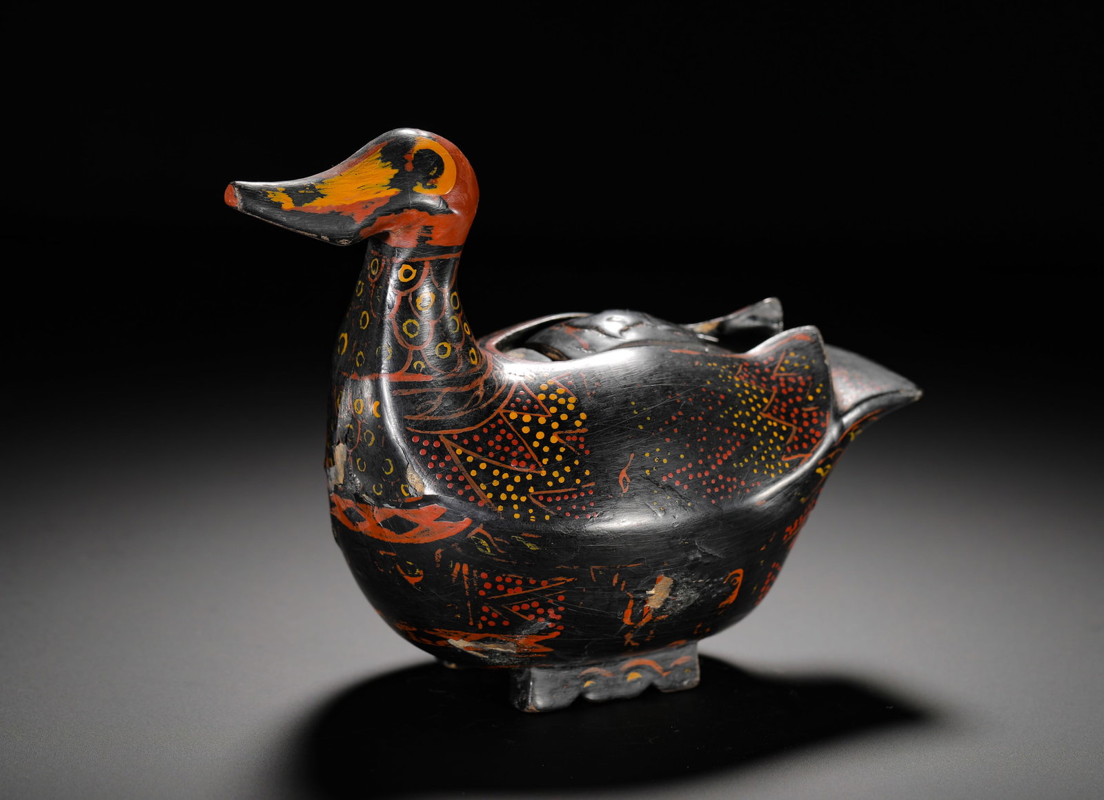 HAN DYNASTY BLACK-GROUND PAINTED MANDARIN DUCK-SHAPED LACQUER BOX: Height:13.5cm (5.31in) Width:16.5cm (6.50in) Weight:180g(0.40lb)Black lacquer duck-shaped box painted with red and yellow feather patterns, fitted lid, antique lacquer container for ink paste or incen