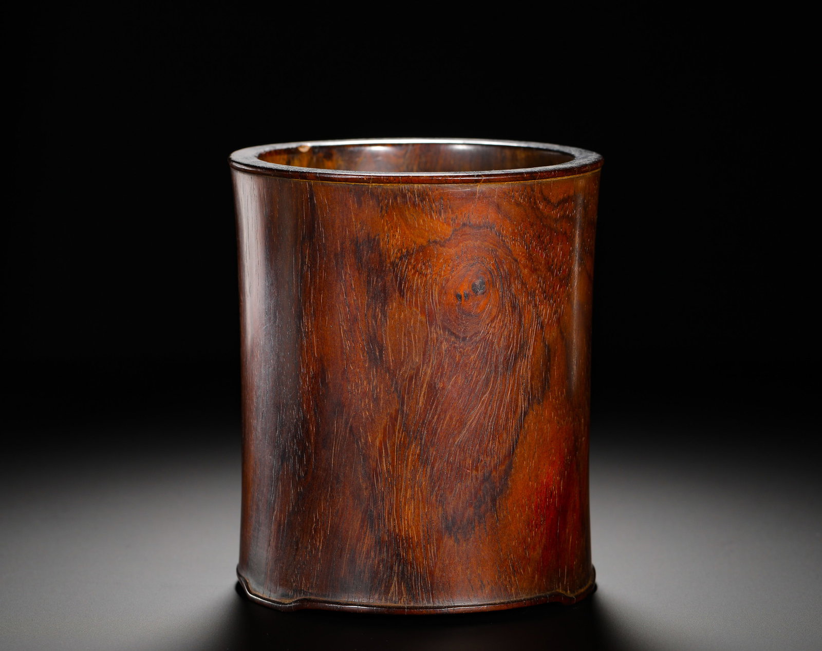 A PLAIN PEN HOLDER MADE OF YELLOW ROSEWOOD FROM THE MING DYNASTY: Height:14cm (5.51in) Width:12cm (4.72in) Weight:440g(0.97lb)Plain Huanghuali wood brush pot with natural circular ghost-eye grain, stringed rim, curved base edges, simple antique desk pen holder.
