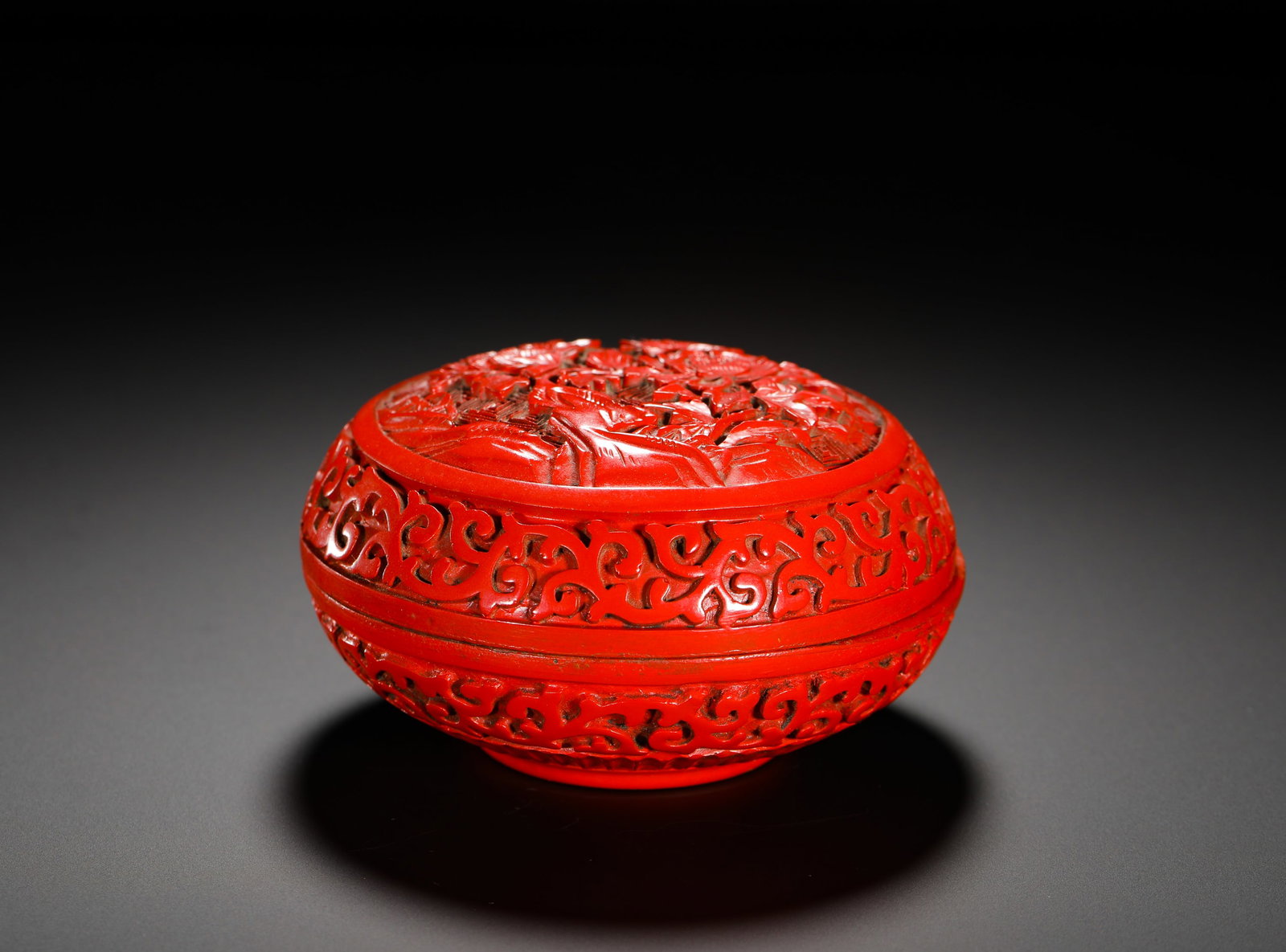 RED LACQUERED ROUND BOX OF THE QING DYNASTY: Height:6cm (2.36in) Width:10.5cm (4.13in) Weight:170g(0.37lb)Red lacquer round box carved with landscape figures on cover, scrolling foliage patterns on sides, inscribed "Collected by Xuhua Hall" on b
