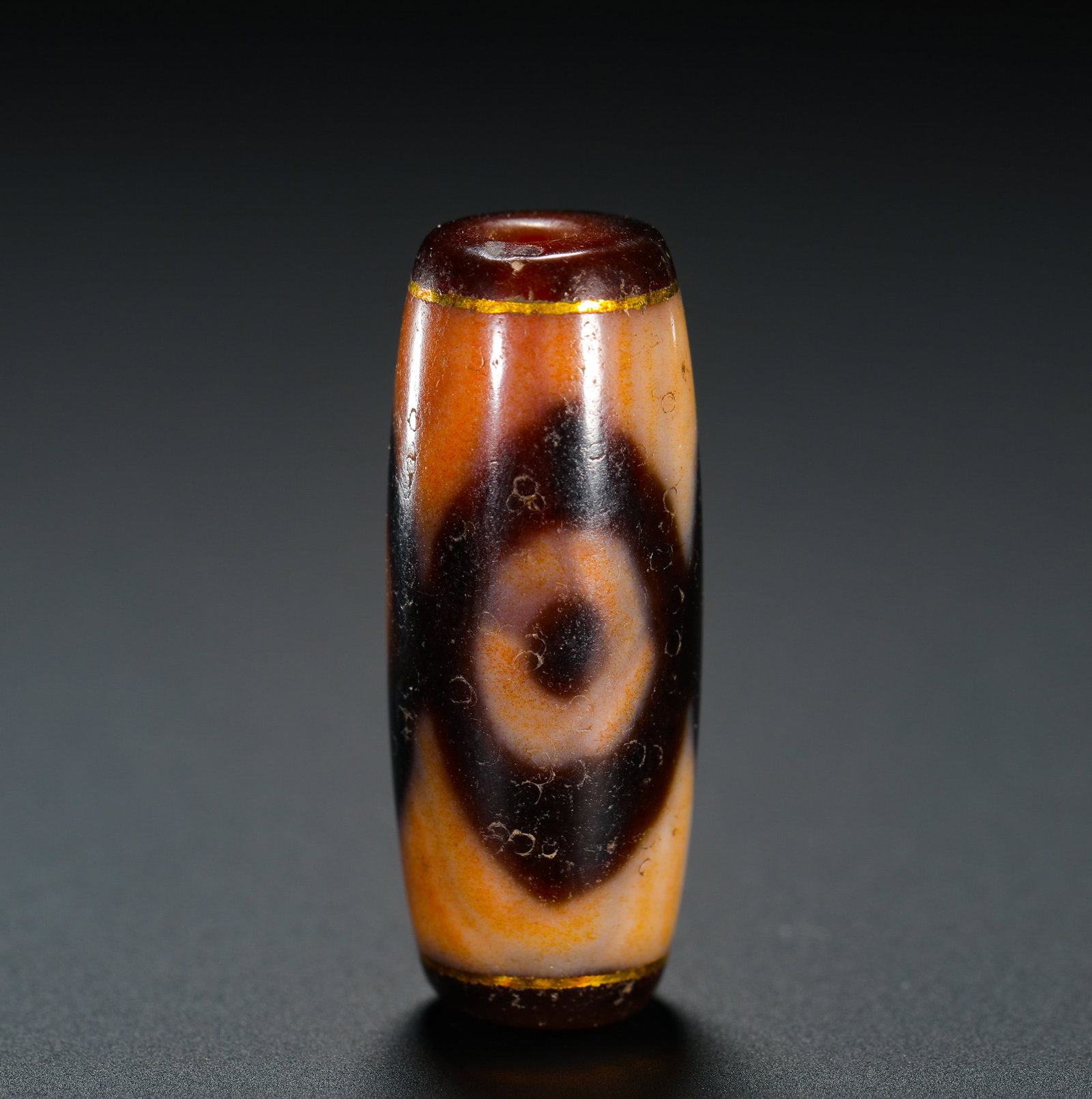 GOLD-INLAID SINGLE-EYED BUDDHA EYE SKY BEADS: Height:3.2cm (1.26in) Weight:9g(0.02lb)Single Buddha-eye dzi bead with gold inlaid rims, made of cylindrical agate naturally stained with warm orange-red patina. A rhombic Buddha-eye totem sits at the