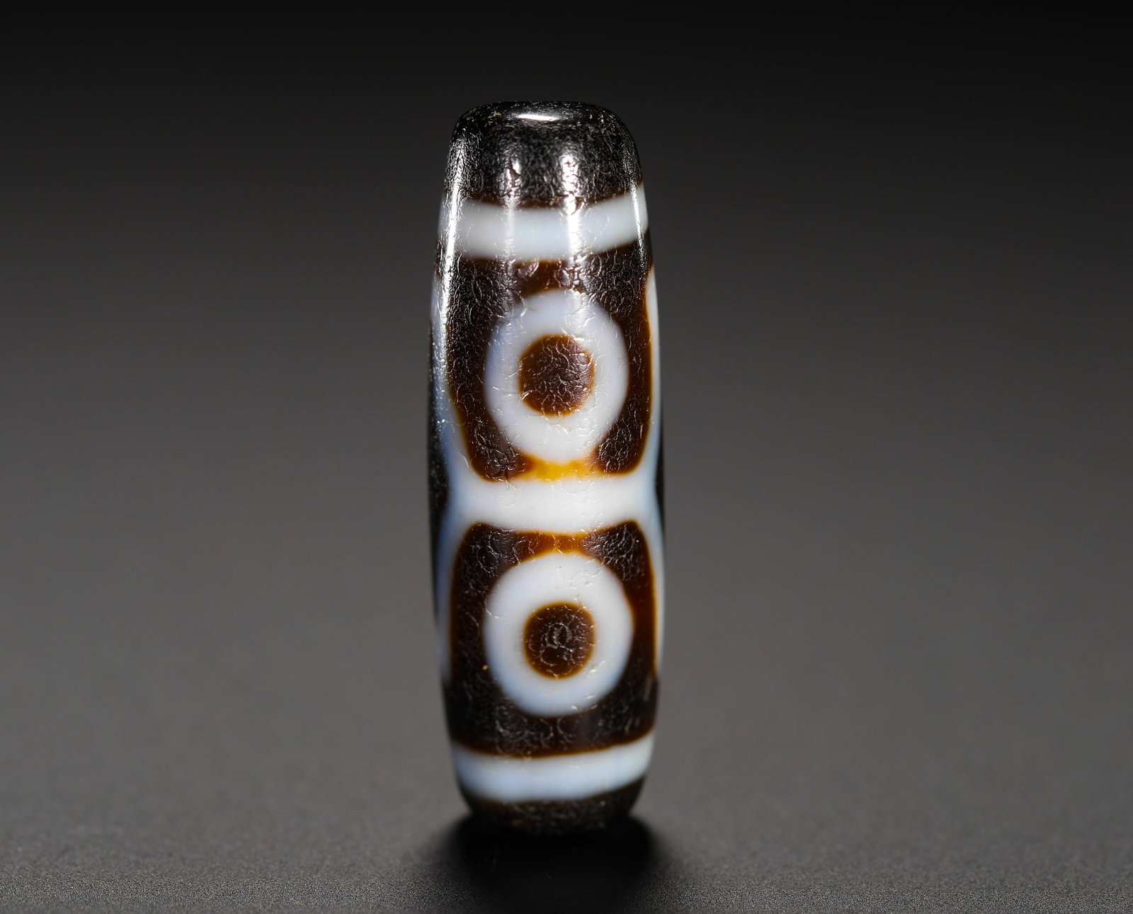 DOUBLE-LINE TWO-EYED SKY BEADS: Height:3.5cm (1.38in) Weight:7g(0.02lb)Two-eye ancient dzi bead with double dividing lines, crafted from elongated agate, etched with two round eye totems in cream white against dark brown base. The b