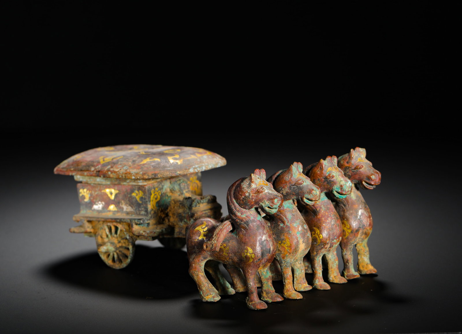 BRONZE WITH GOLD INLAID FOUR-HORSE CHARIOT ORNAMENT FROM THE WARRING STATES PERIOD: Height:7cm (2.76in) Width:20cm (7.87in) Weight:1060g(2.34lb)Warring States bronze ornament of four horses drawing a carriage. Cast in bronze, the piece features four steeds pulling a covered carriage 