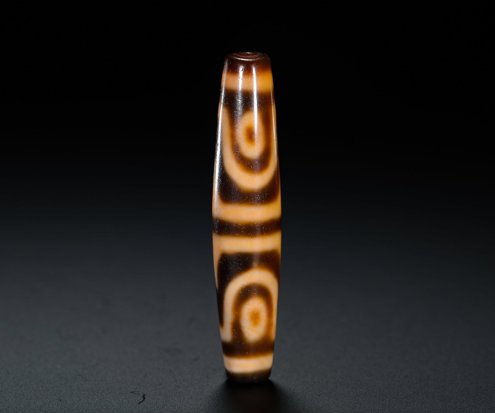 DOUBLE-LINE TWO-EYED SKY BEADS: Height:6cm (2.36in) Weight:13g(0.03lb)Two-eye ancient dzi bead with double dividing lines, crafted in elongated shuttle-shaped agate, etched with dark brown and cream totem patterns. The bead surface 