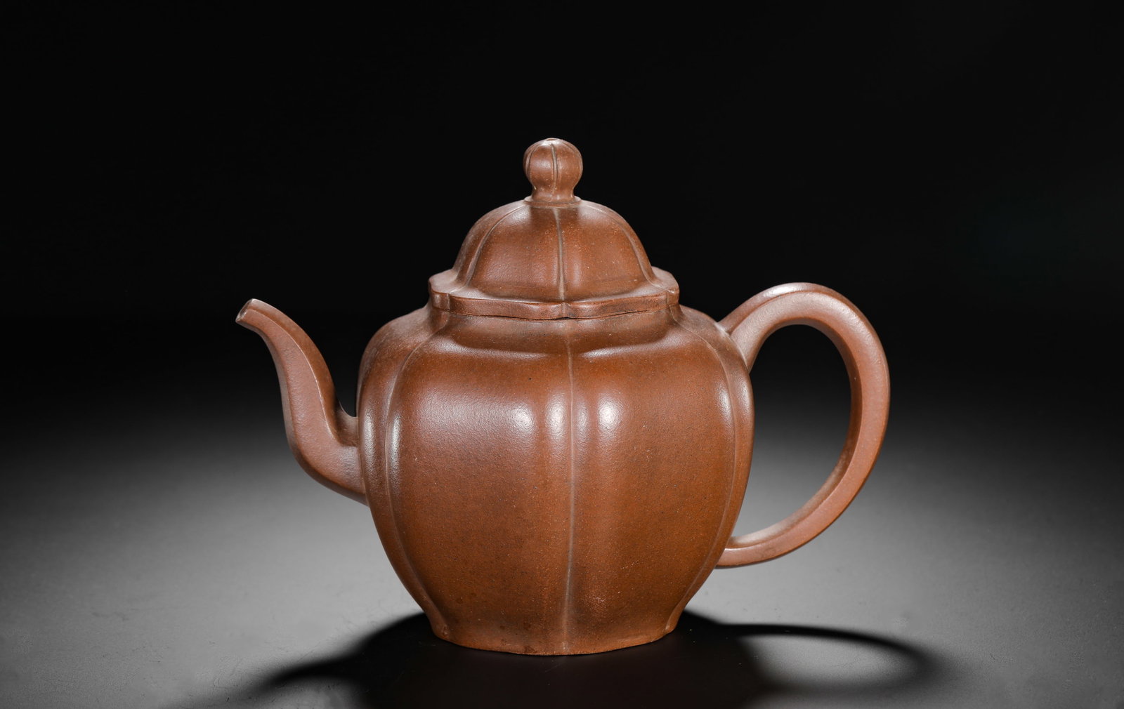 A SIX-PETAL RHOMBUS-SHAPED PURPLE CLAY TEAPOT MADE DURING THE REIGN OF EMPEROR QIANLONG OF THE QING: H:14.5cm W:18.5cm Weight:410g Classic ribbed Zisha teapot made of aged natural purple clay, shaped as six-petal rhombus. Rib lines run straight from base to lid top with neat full curves. The lid and 