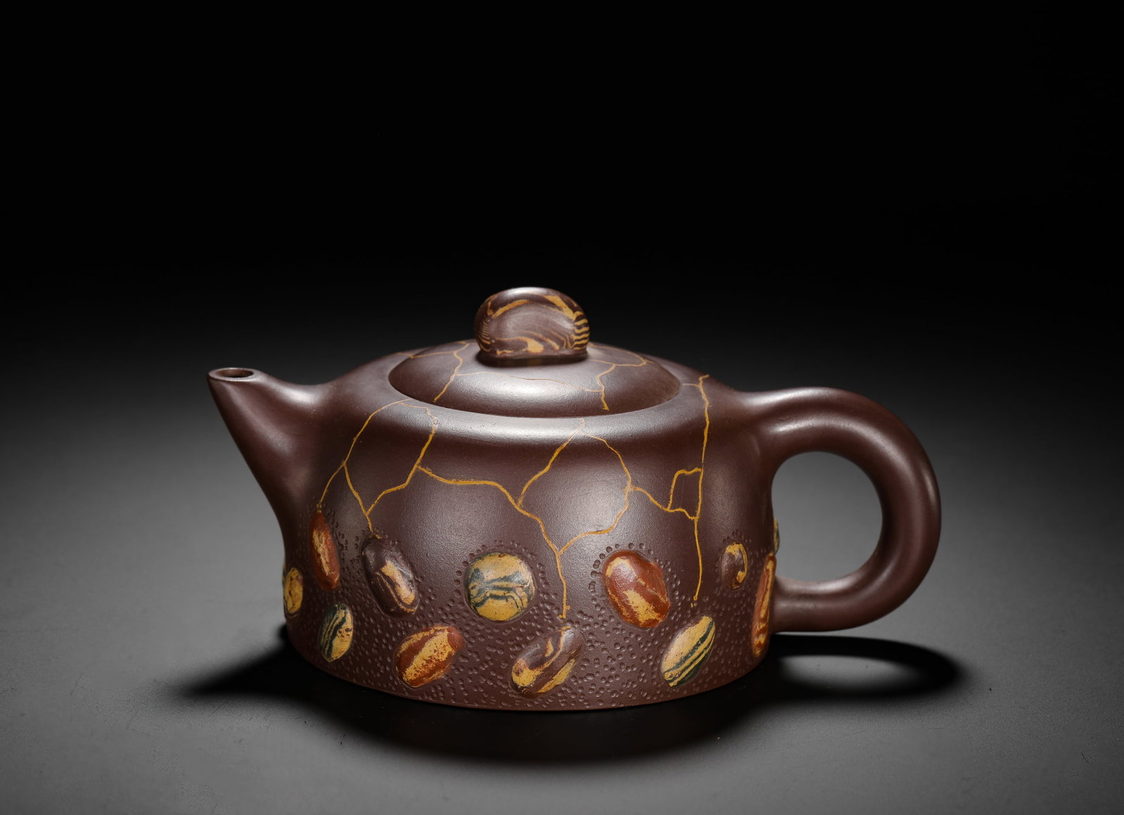 LU YAOCHEN'S SHIPIAO PURPLE CLAY TEAPOT: H:9cm W:17cm Weight:390g Innovative decorated Shipiao teapot based on natural dark purple clay base. The lower body is textured with pitted grain and inlaid with multi-color marbled pebble inlays of n