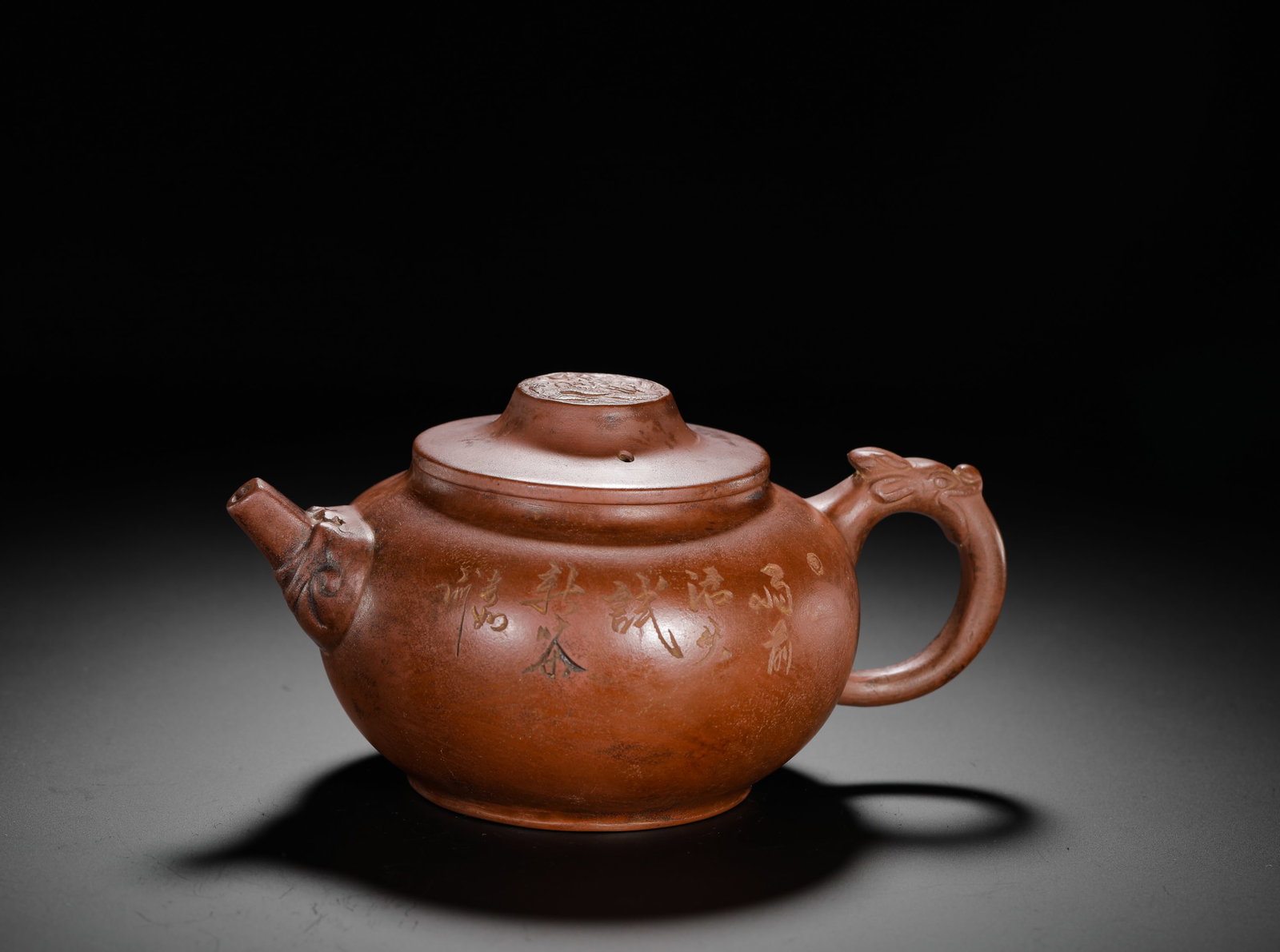 ZHU KEXIN LONGHANDLE PURPLE CLAY TEAPOT: H:9cm W:18.5cm Weight:380g Traditional Zisha teapot with beast handle and literati engraving, crafted from natural red clay with plump rounded body. The circular handle is sculpted into a vivid dragon