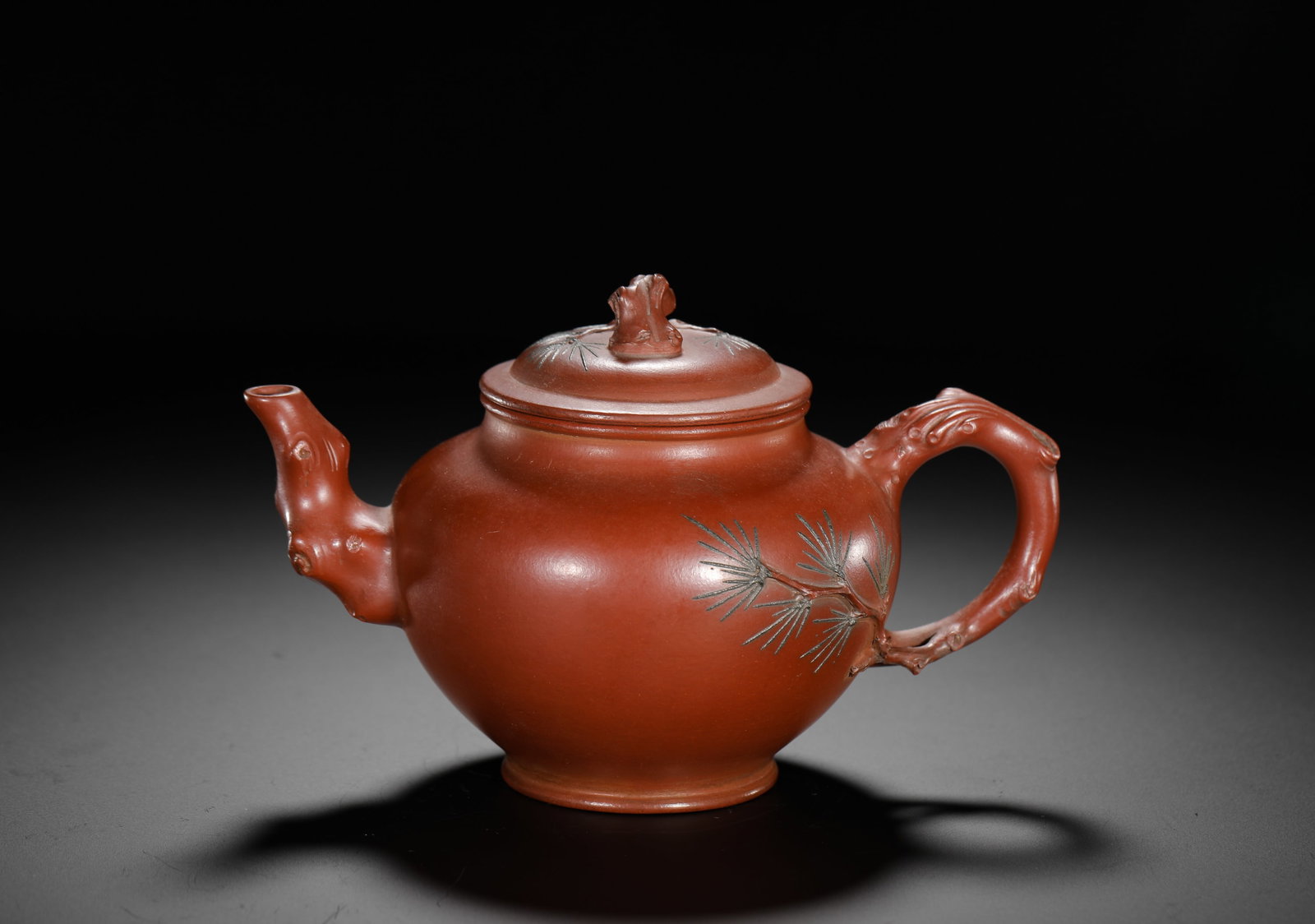 ZHU KEXIN SONGZHUANG PURPLE CLAY TEAPOT: H:11cm W:16cm Weight:270g Traditional floral Zisha teapot crafted from fine natural vermilion clay. Plump rounded body, spout, handle and lid knob modelled as gnarled aged pine trunk roots. Pine branc