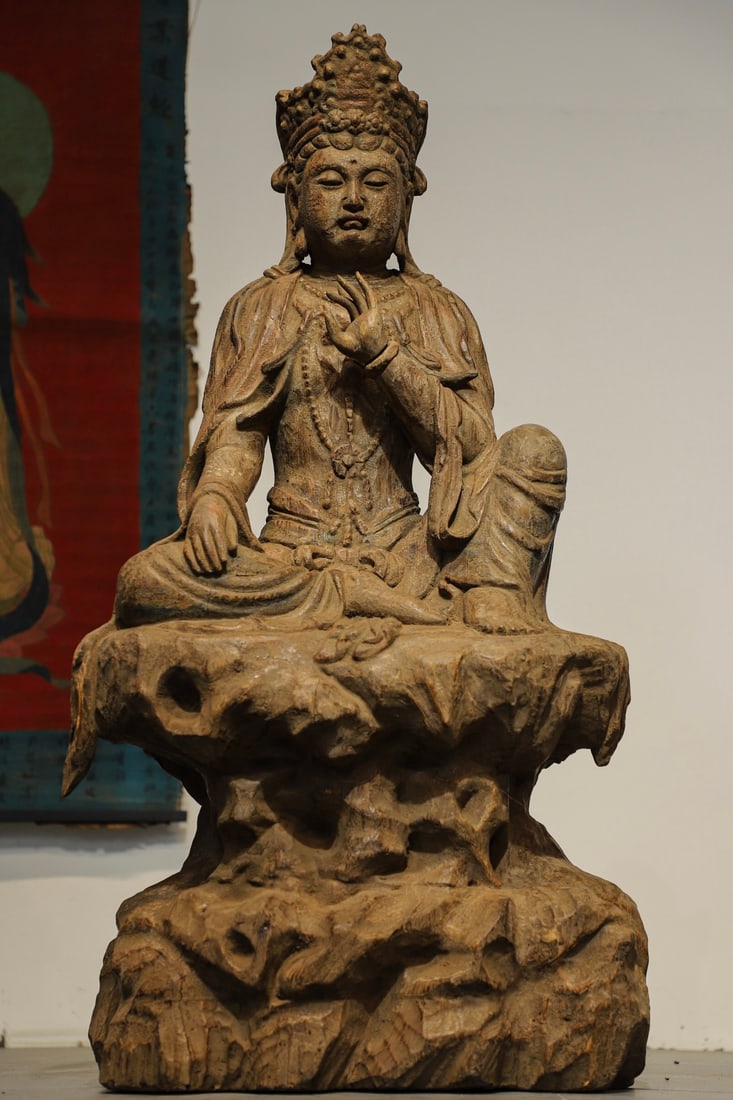 SEATED STATUE OF GUANYIN IN NANMU, MING DYNASTY: H:110cm L:58cm W:40cm The face of this statue is round and full, with a serene and kind expression. The lines of the clothing are smooth and flowing, featuring both the dignity of Ming Dynasty statues