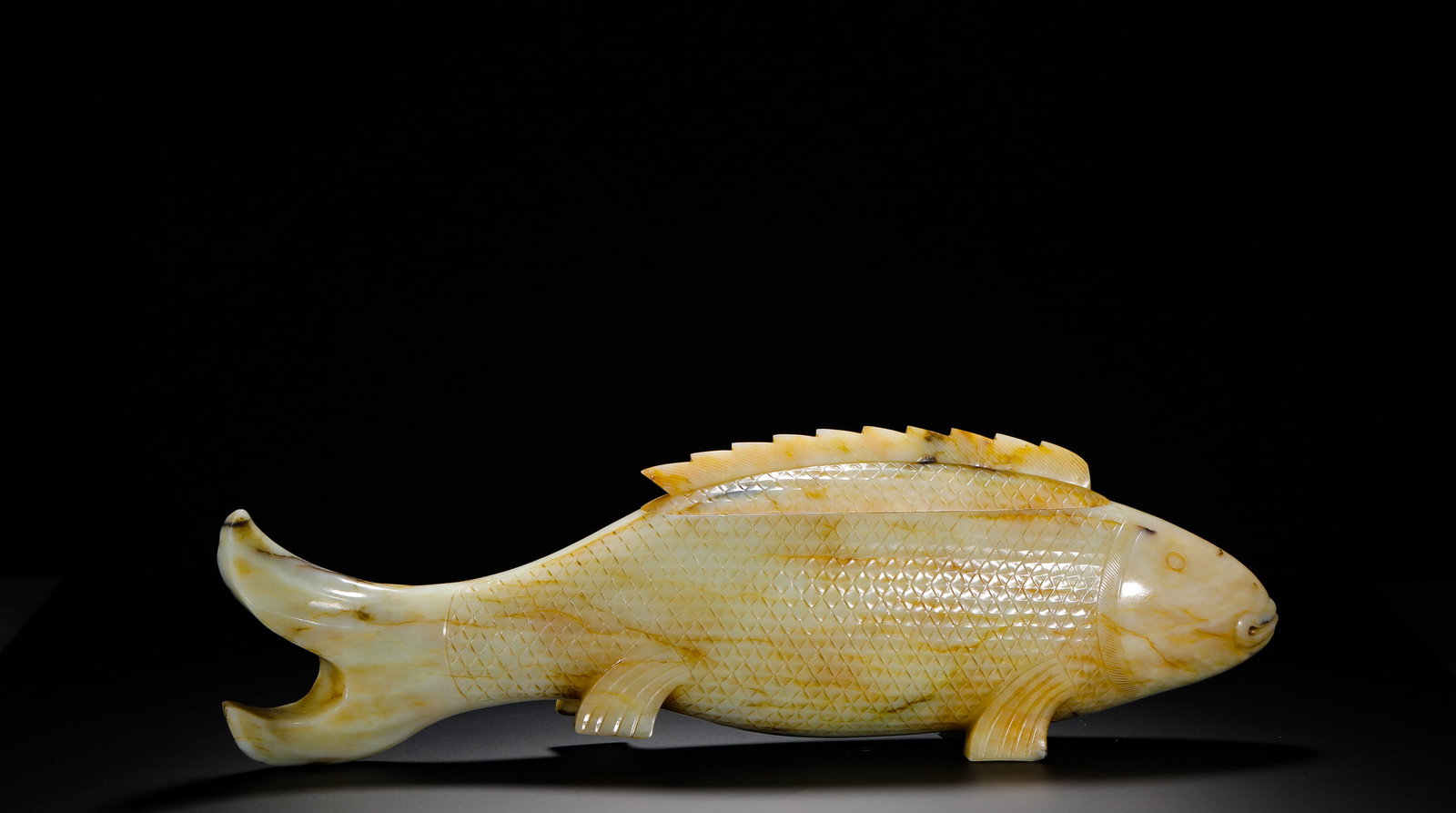 TANG DYNASTY HETIAN JADE FISH-SHAPED LID BOX: Height:13cm (5.12in) Width:41cm (16.14in) Weight:2980g(6.57lb)Ancient Hetian white jade carp-shaped covered incense box, hollow carved from whole jade with separate fin lid. Fine scaled line engraving