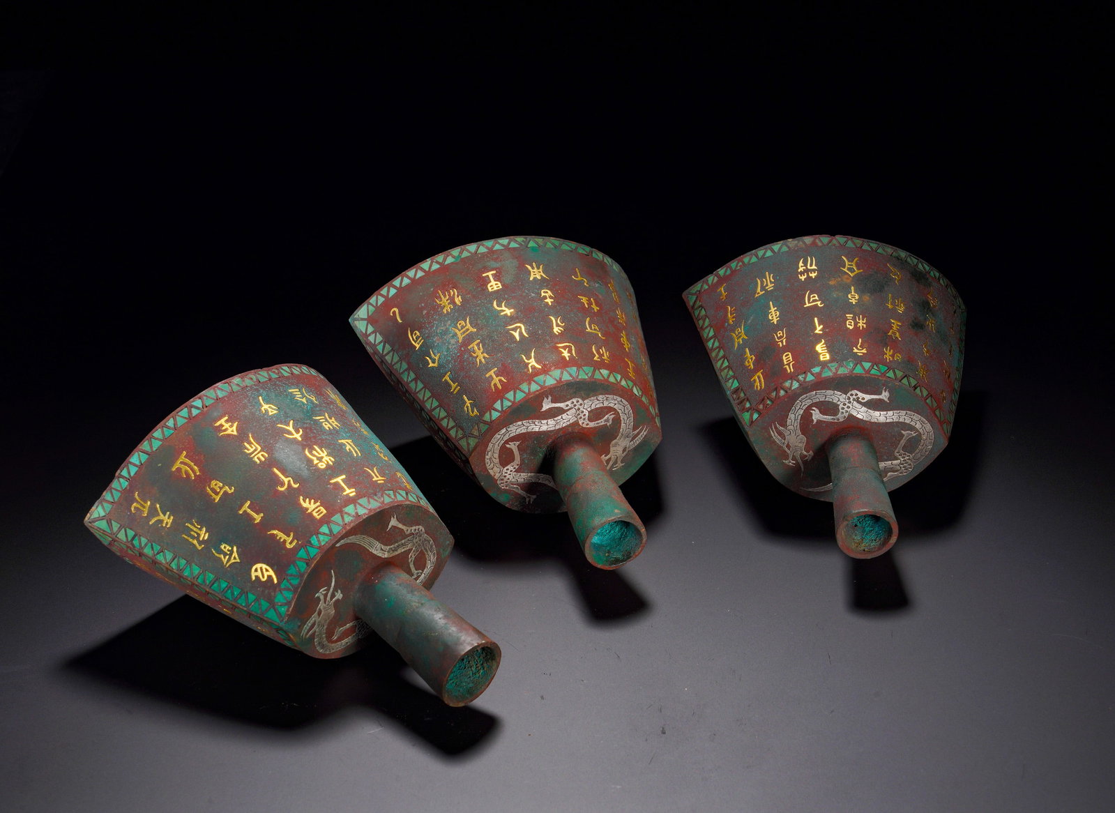 BRONZE BELLS WITH INLAID GOLD AND SILVER INSCRIPTIONS FROM THE WARRING STATES PERIOD: Height:15cm (5.91in) Width:11cm (4.33in) Weight:1710g(3.77lb)Cylindrical bronze chariot hardware mounted on axle terminals. Surfaces decorated with intertwined dragon motifs outlined by gold and silve