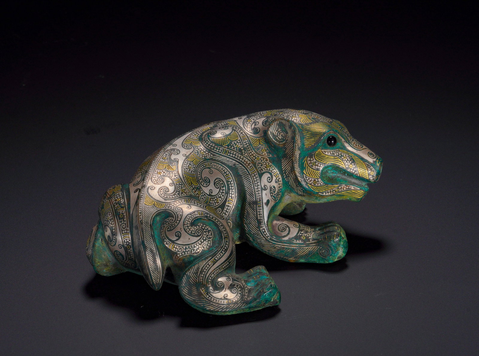 HAN DYNASTY BRONZE INLAID GOLD AND SILVER AUSPICIOUS BEAST BEAR TOWN: Height:5.5cm (2.17in)Width:11.5cm (4.53in)Weight:1020g(2.25lb)Han Dynasty bronze bear weight with gold and silver inlay.The recumbent bear is decorated with elaborate interlocking scroll patterns inla