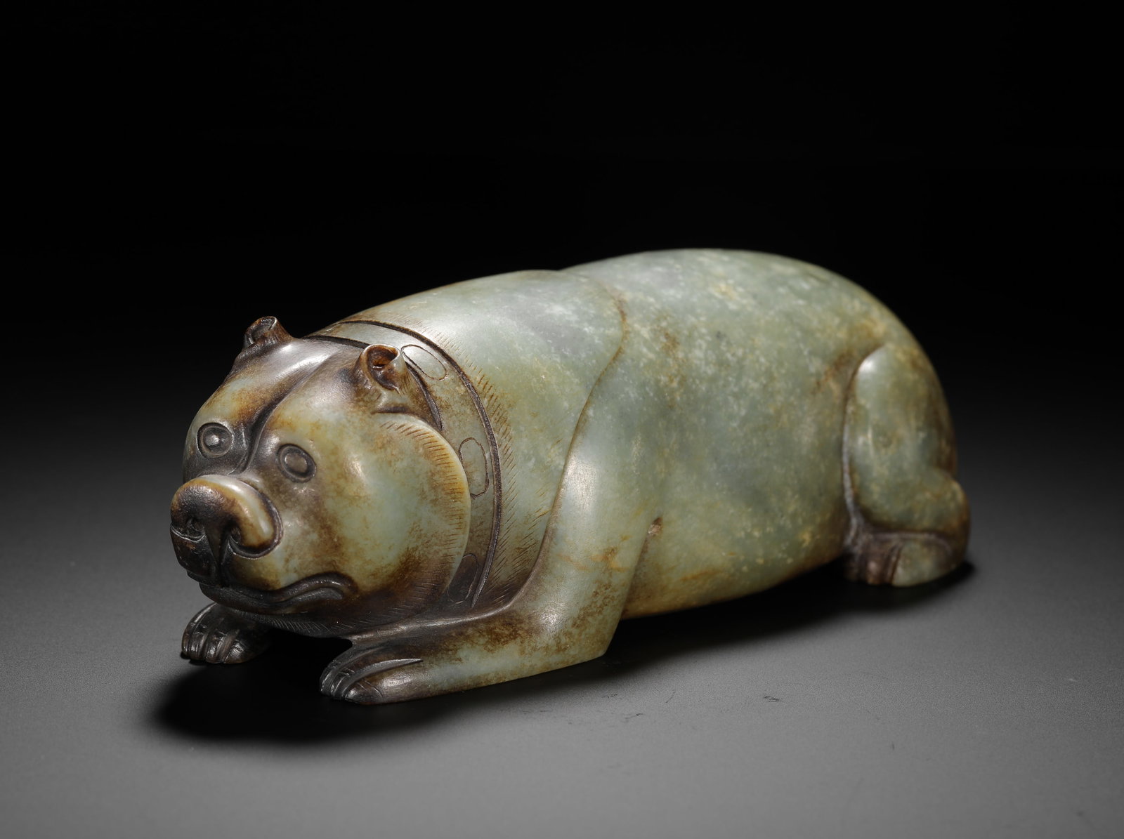 HAN DYNASTY HETIAN JADE LYING BEAR: H:5.5cm W:17.5cm Weight:1360g Round-carved Han jade bear with carved collar and aged brown patina, symbolizing strength and auspiciousness for noble display.