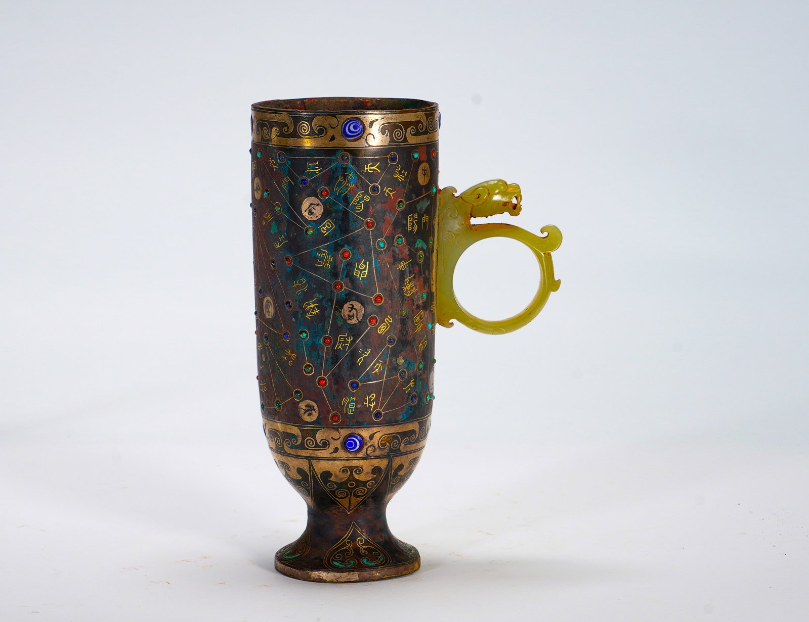 BRONZE CUPS WITH GOLD INLAID ASTRONOMICAL STARS AND JADE HANDLES FROM THE WARRING STATES PERIOD: Height:15.5cm (6.10in) Width:11cm (4.33in) Weight:490g(1.08lb)Tall bronze drinking cup fitted with pale yellow jade dragon loop handle. Golden wire celestial constellation chart spread across body, co