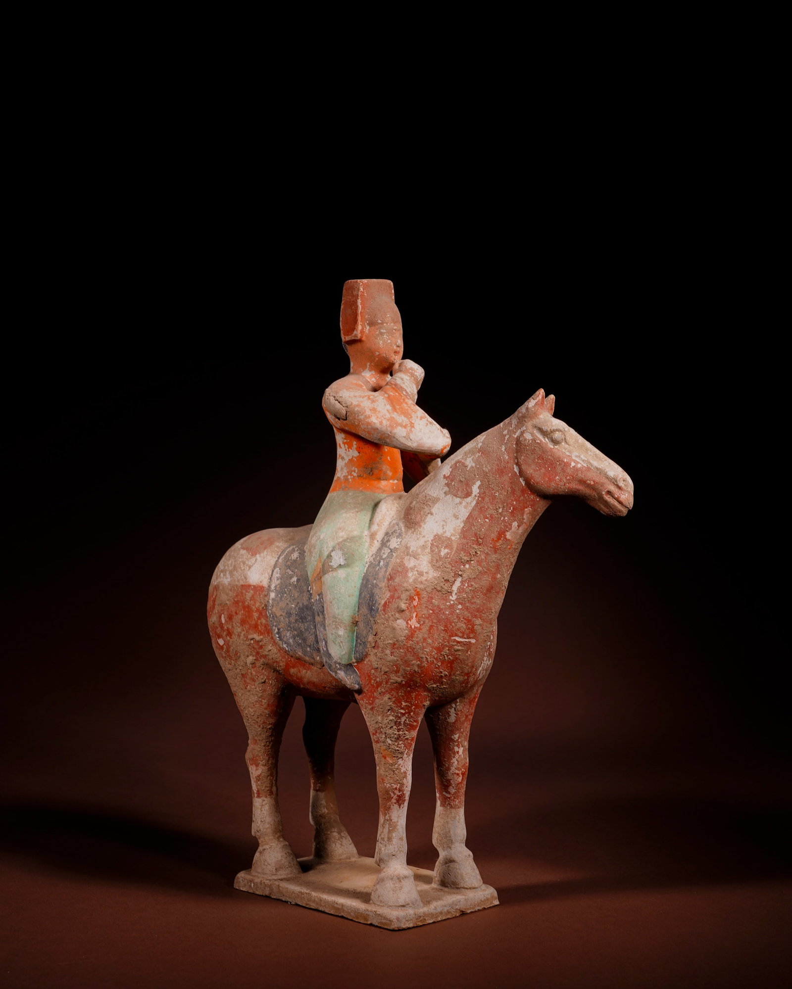 PAINTED POTTERY FIGURINES OF HORSE-RIDING OFFICIALS FROM THE MING DYNASTY: L:21cm H:27cm This painted pottery equestrian official figurine of Ming Dynasty is made of white clay, painted with mineral pigments and fired as an integrated piece with rectangular base.The figure w