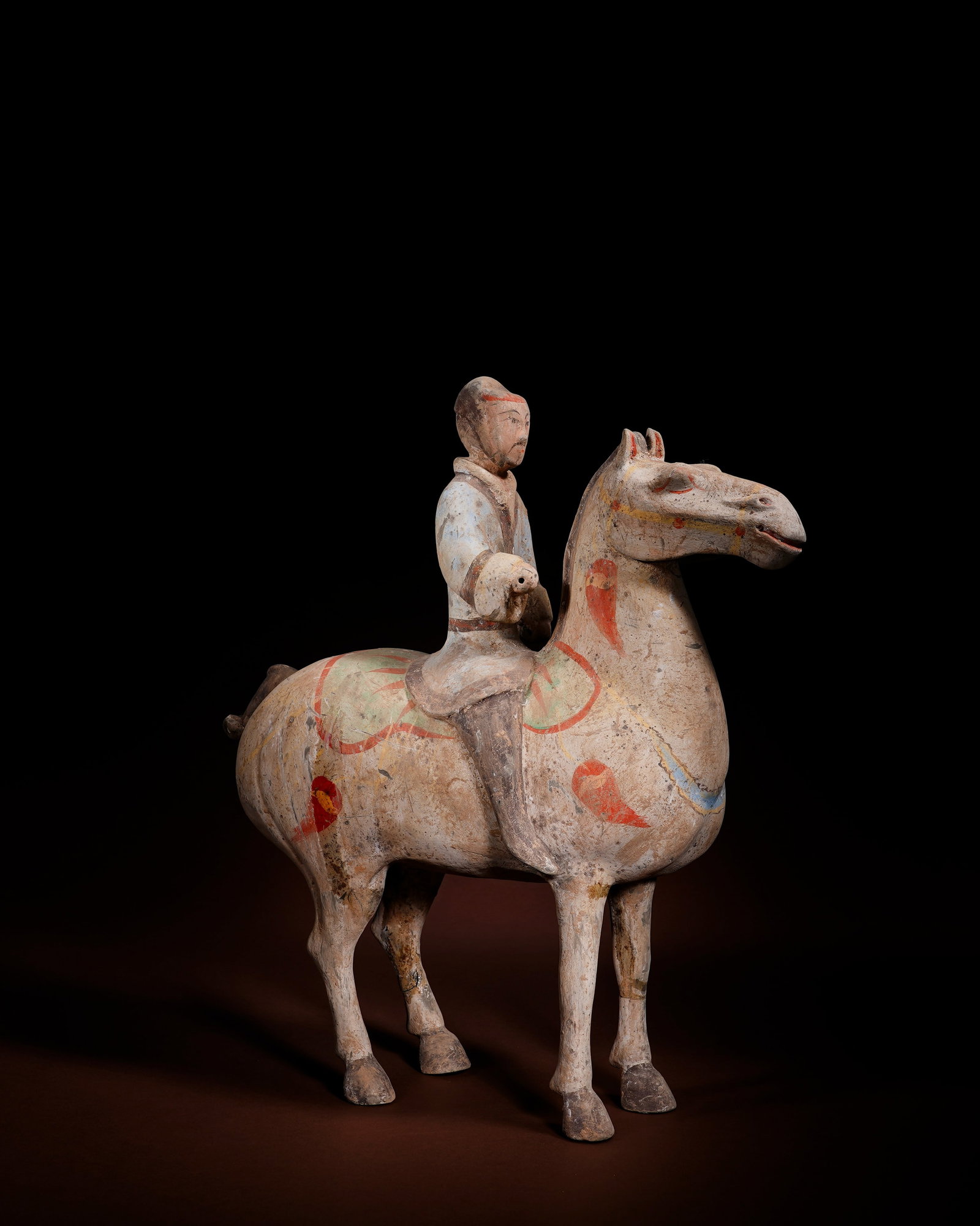 PAINTED TERRACOTTA WARRIORS OF THE HAN DYNASTY: L:34cm H:36cm This painted pottery equestrian warrior figurine of Han Dynasty is molded in separate parts then assembled, without base, decorated with red, yellow and blue mineral pigments on plain cl