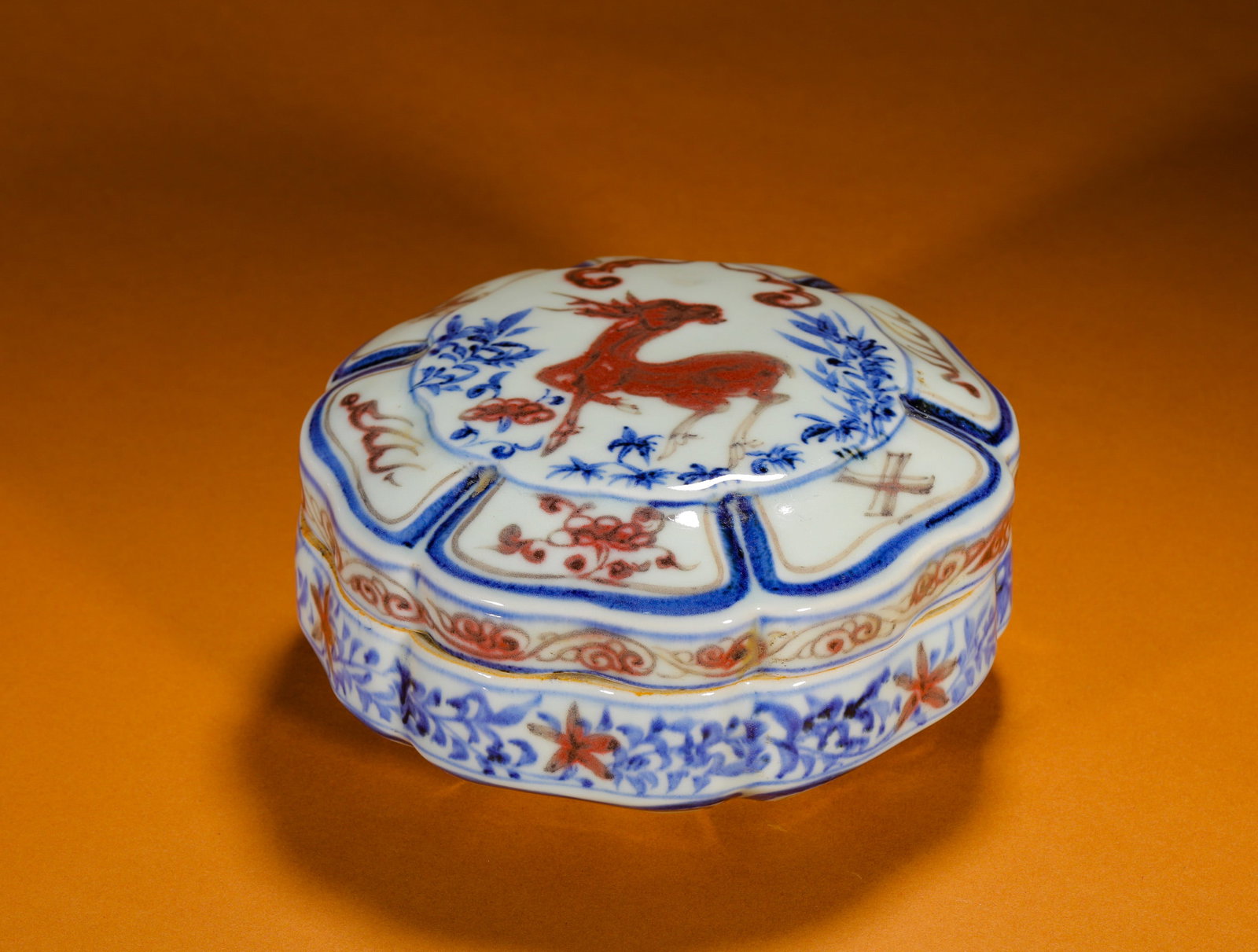 BLUE AND WHITE UNDERGLAZE RED DEER FLOWER SHAPE SEAL BOX: Height:8cm (3.15in)Diameter:15cm (5.91in)Weight:570g(1.26lb)Blueandunderglazeredflower-shapedsealboxwithdeer&lingzhimotif.Multi-lobedrhombusflowerformwithtightfittinglid, shallowflatbelly, delicaterou