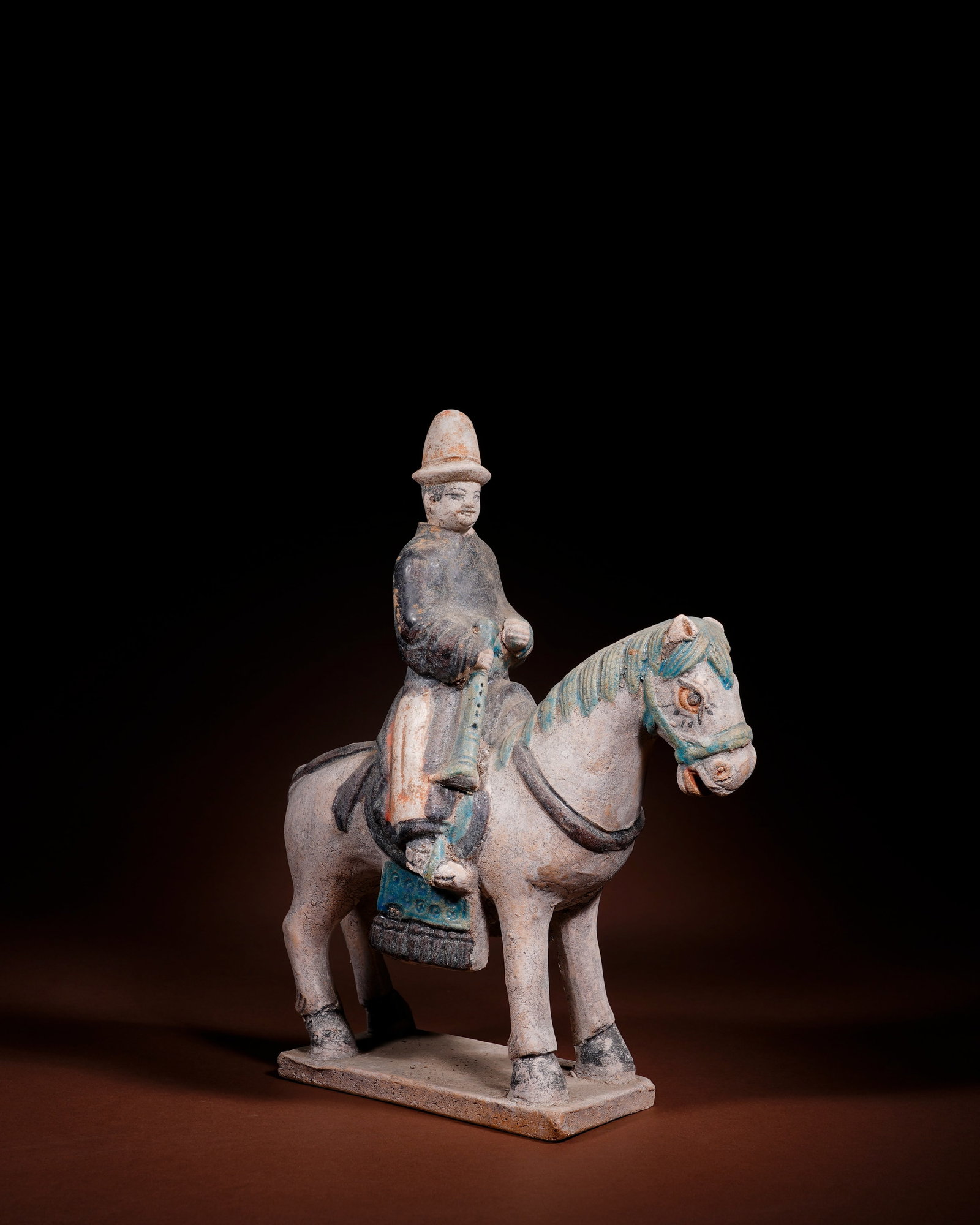 PLAIN TRICOLOR FIGURINES OF HU PEOPLE RIDING AND PLAYING: L:21.5cm H:26cm This low-temperature plain tri-color burial figurine of Western Regions musician riding horse is made of white pottery clay, integrated with horse and rectangular base in one firing, g