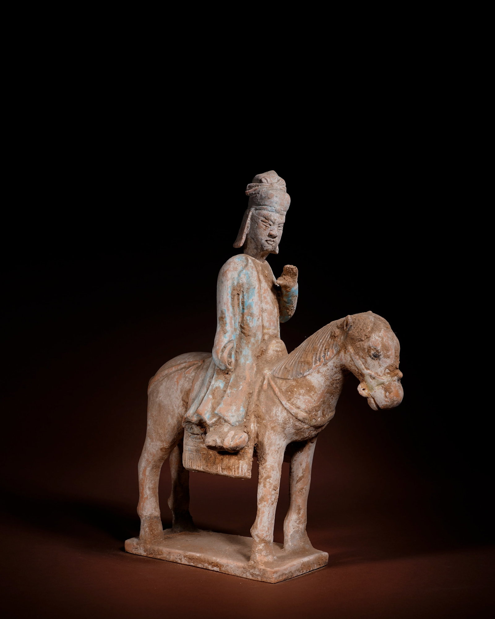 BLUE PAINTED CIVIL OFFICIAL ON HORSEBACK TERRACOTTA FIGURINES OF THE MING DYNASTY: L:27cm H:37cm This painted equestrian civil official figurine of Ming Dynasty is made of white clay, integrated with horse and rectangular base in one firing, partially decorated with mineral blue pig