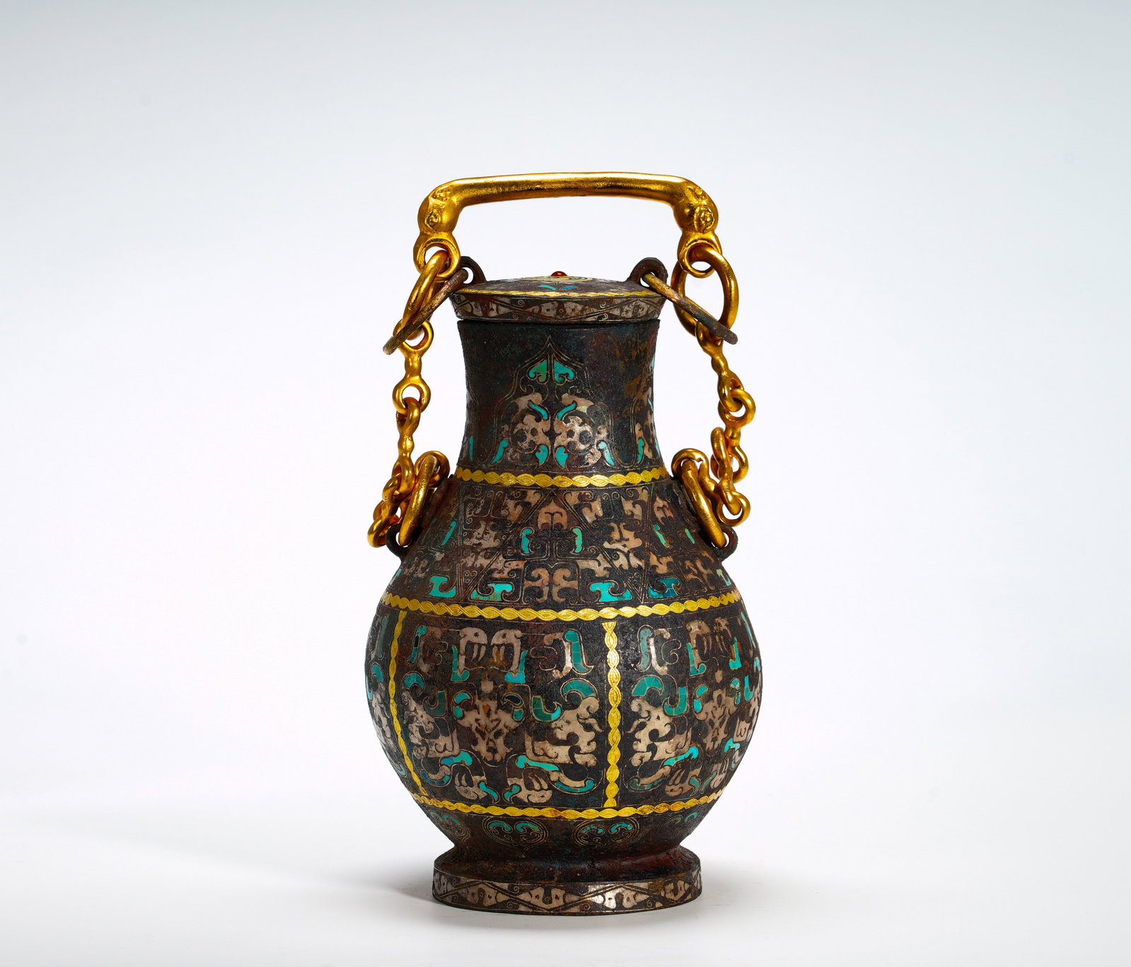 BRONZE WITH TURQUOISE AND GILDED CHAIN-CARRYING POT FROM THE WARRING STATES PERIOD: Height:22cm (8.66in) Width:14cm (5.51in) Weight:2290g(5.05lb)Bulbous bronze wine pot fitted with golden beast-head chain handle. Inlaid turquoise, gold and silver ornament, interlaced mythical beast p