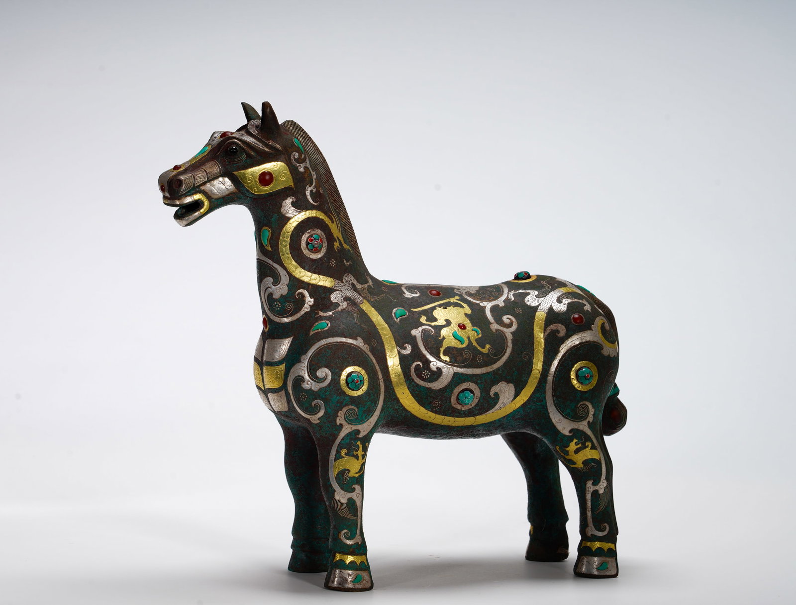 BRONZE FROM THE WARRING STATES PERIOD WITH INLAID GOLD AND SILVER INLAID WITH PRECIOUS HORSES: Height:28cm (11.02in) Width:30cm (11.81in) Weight:2860g(6.31lb)Realistic standing equine statue. Body decorated with interlaced dragon scrolls in gold and silver wire, colorful gem inlays. Horse symbo