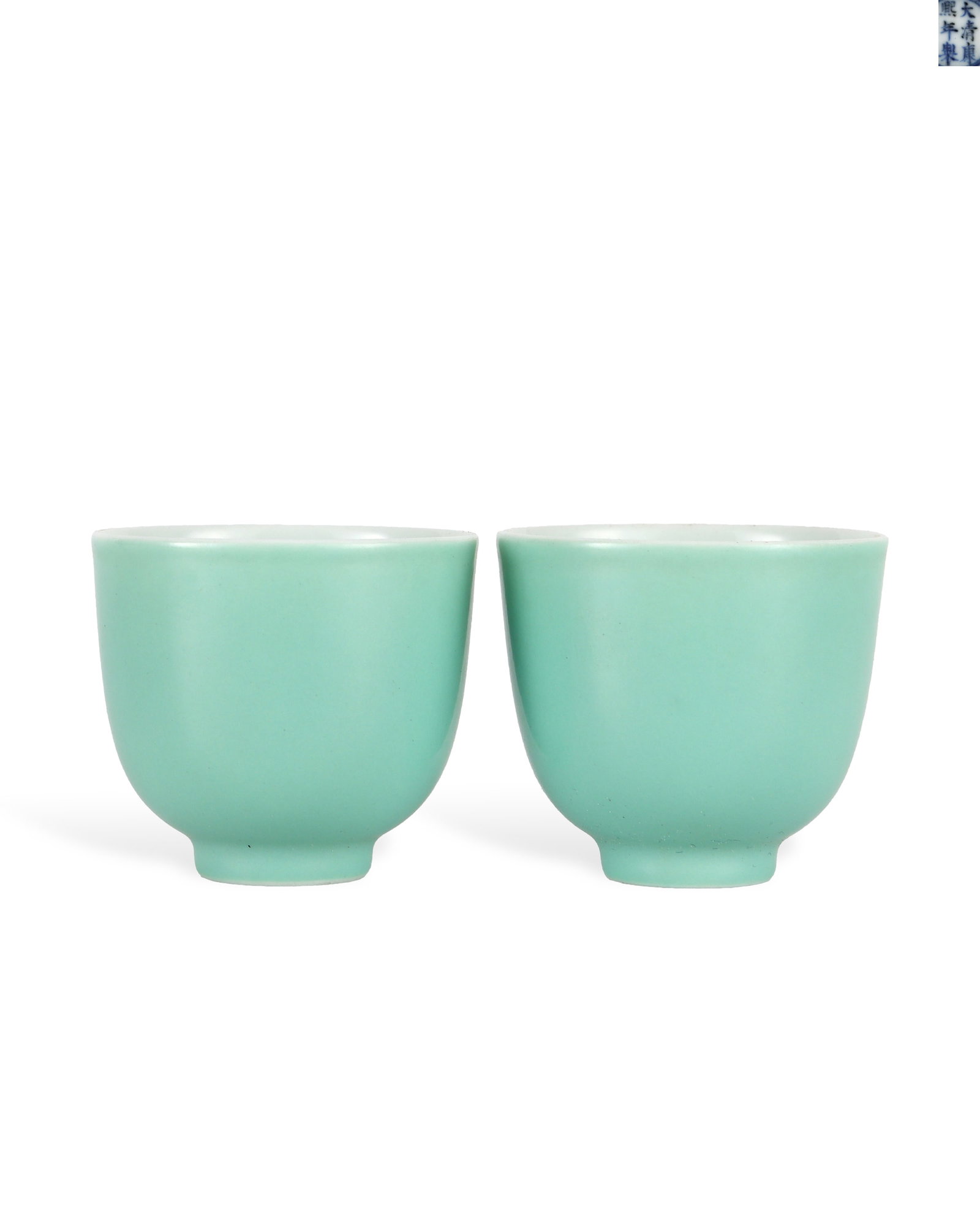 A PAIR OF CUPS WITH TURQUOISE GREEN GLAZE FROM THE KANGXI PERIOD OF THE QING DYNASTY: H:3.9cm W:4.3cm Each cup bears six-character regular script blue-and-white mark "Made in the Kangxi Reign of the Great Qing" within double blue circles on the white glazed base.Turquoise green is a lo